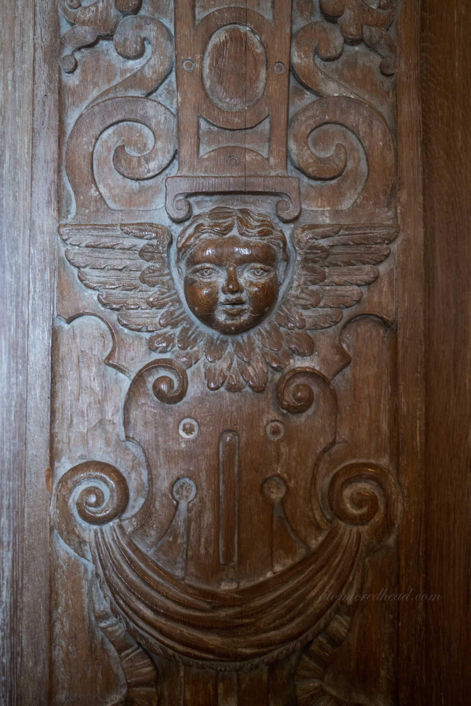 A carved cherub face in the wood paneling of the living room.