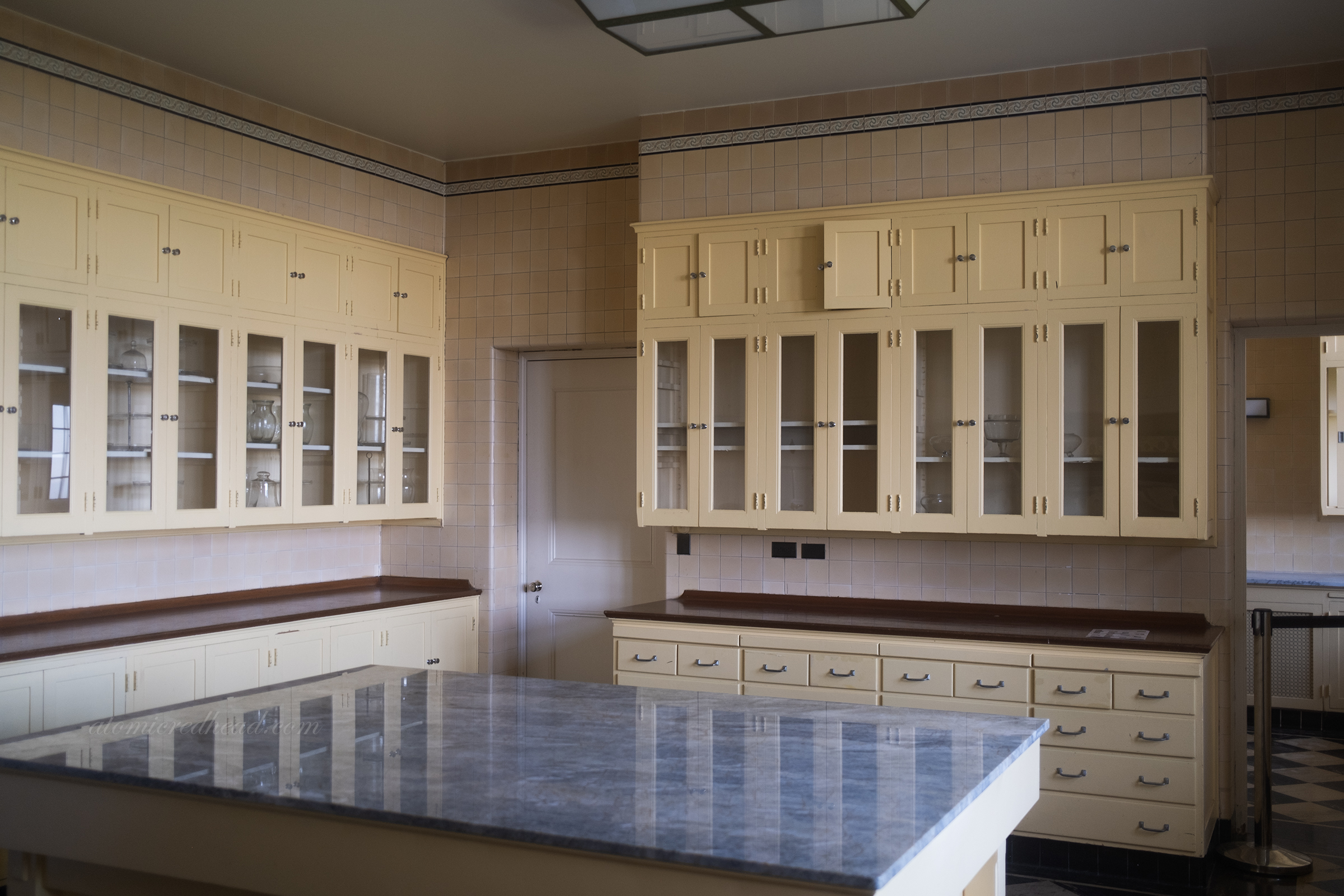 Overall of the kitchen, with pale yellow cabinets and a massive island in the center.