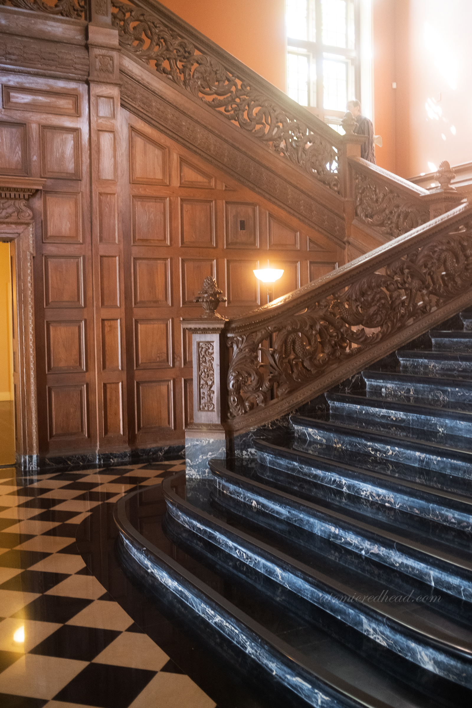 Black marble staircase with carved oak designs along the railing of the entry.