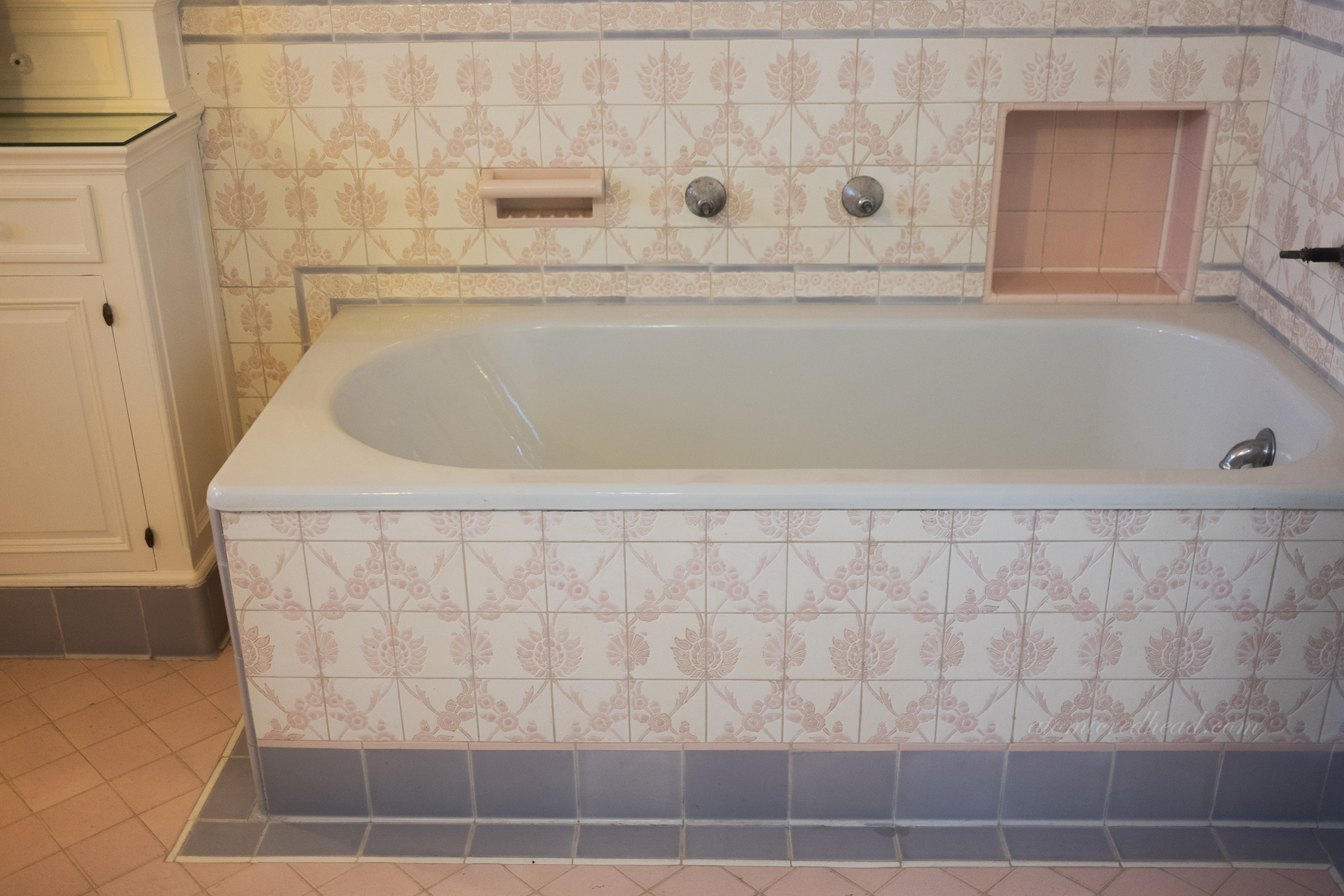Pale pink and white tile with a floral design in a bathroom.