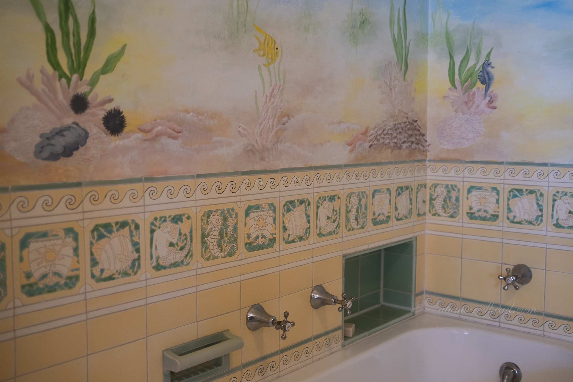 A sea animal theme in tile and mural in a bathroom.