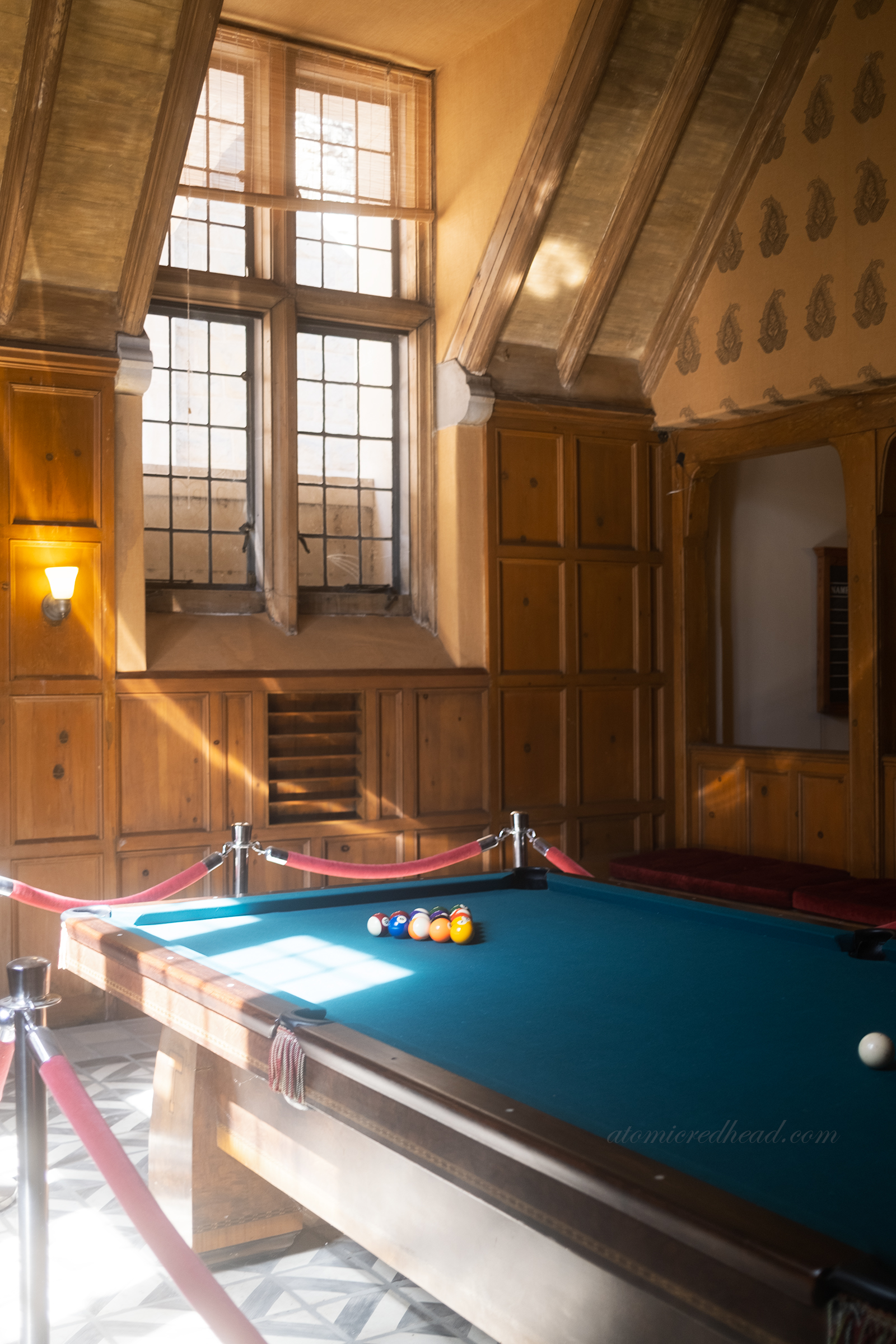 View of the billiard table in a lavish wood paneled room.