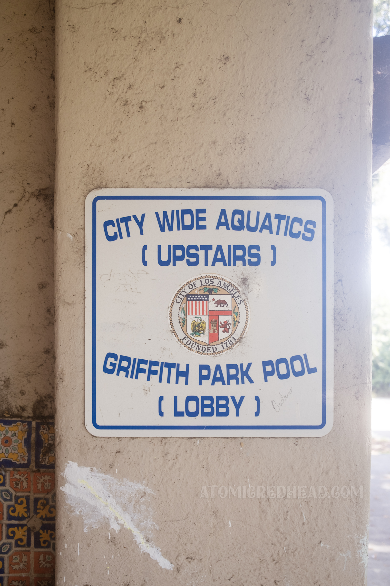 A blue and white sign reads "City Wide Aquatics (upstairs) Griffith Pool (lobby)"