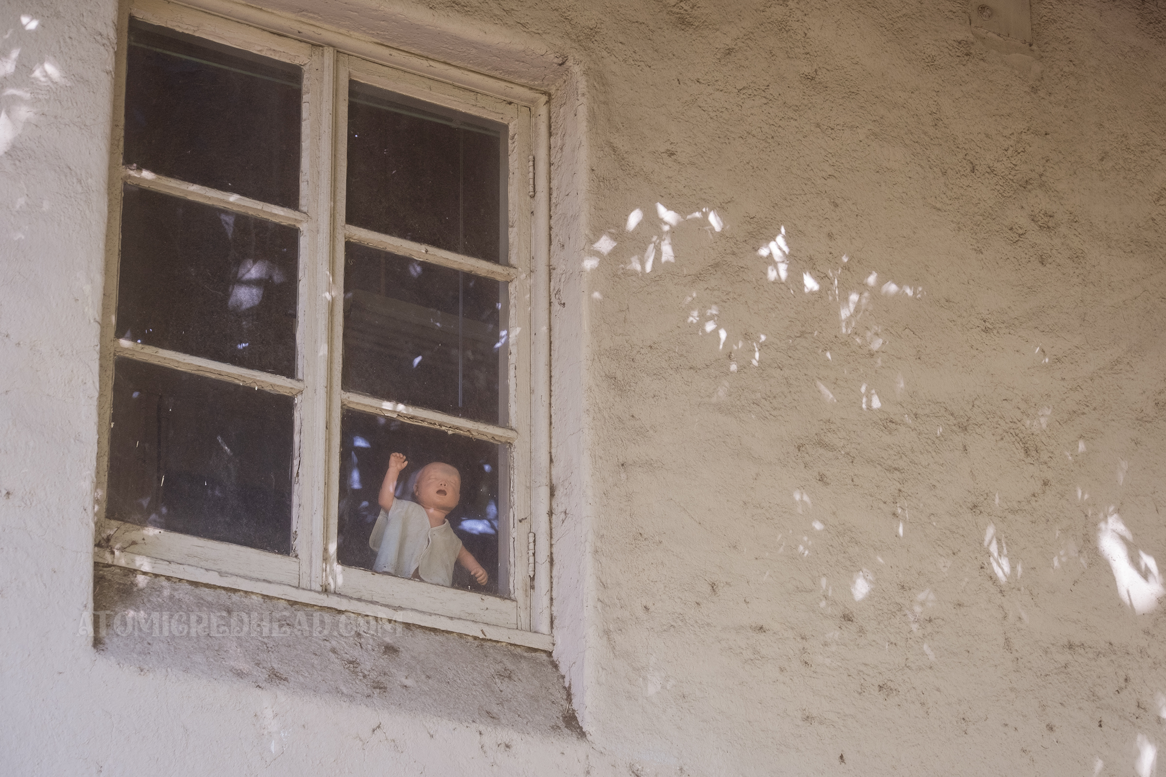 A child size CPR dummy looks out from a second story window in the pool house.