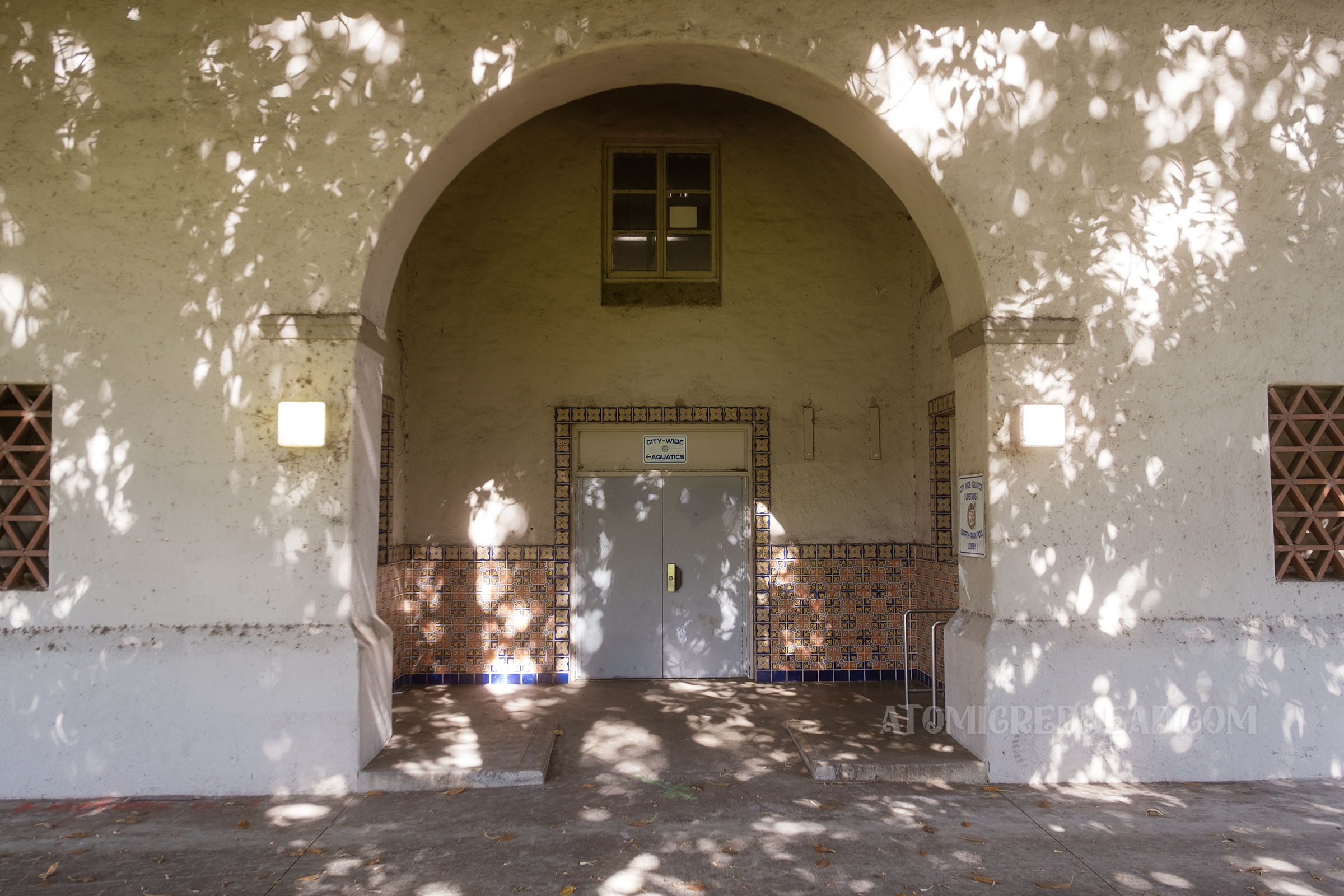 Close-up of the arched entry to the pool house, with multicolored tile around the entry door.