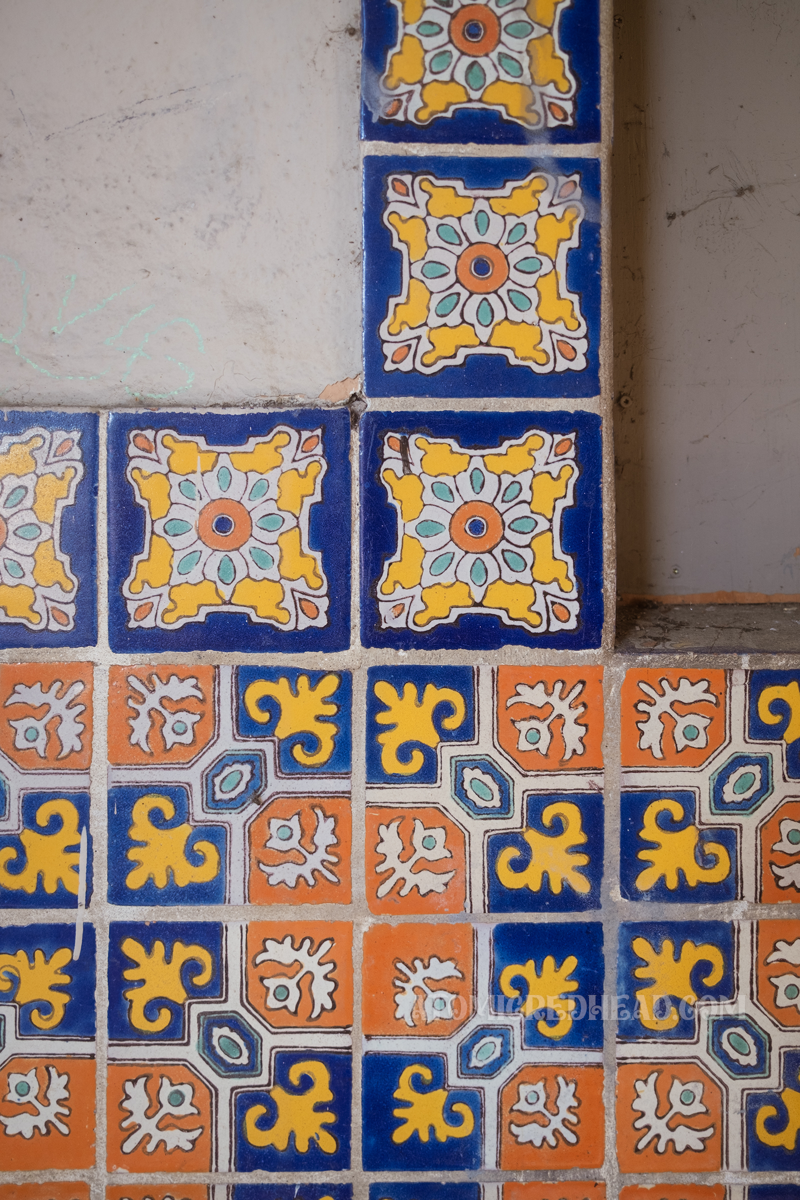Close-up of the decorative colorful tile around the boarded up window, done in a Spanish motif.