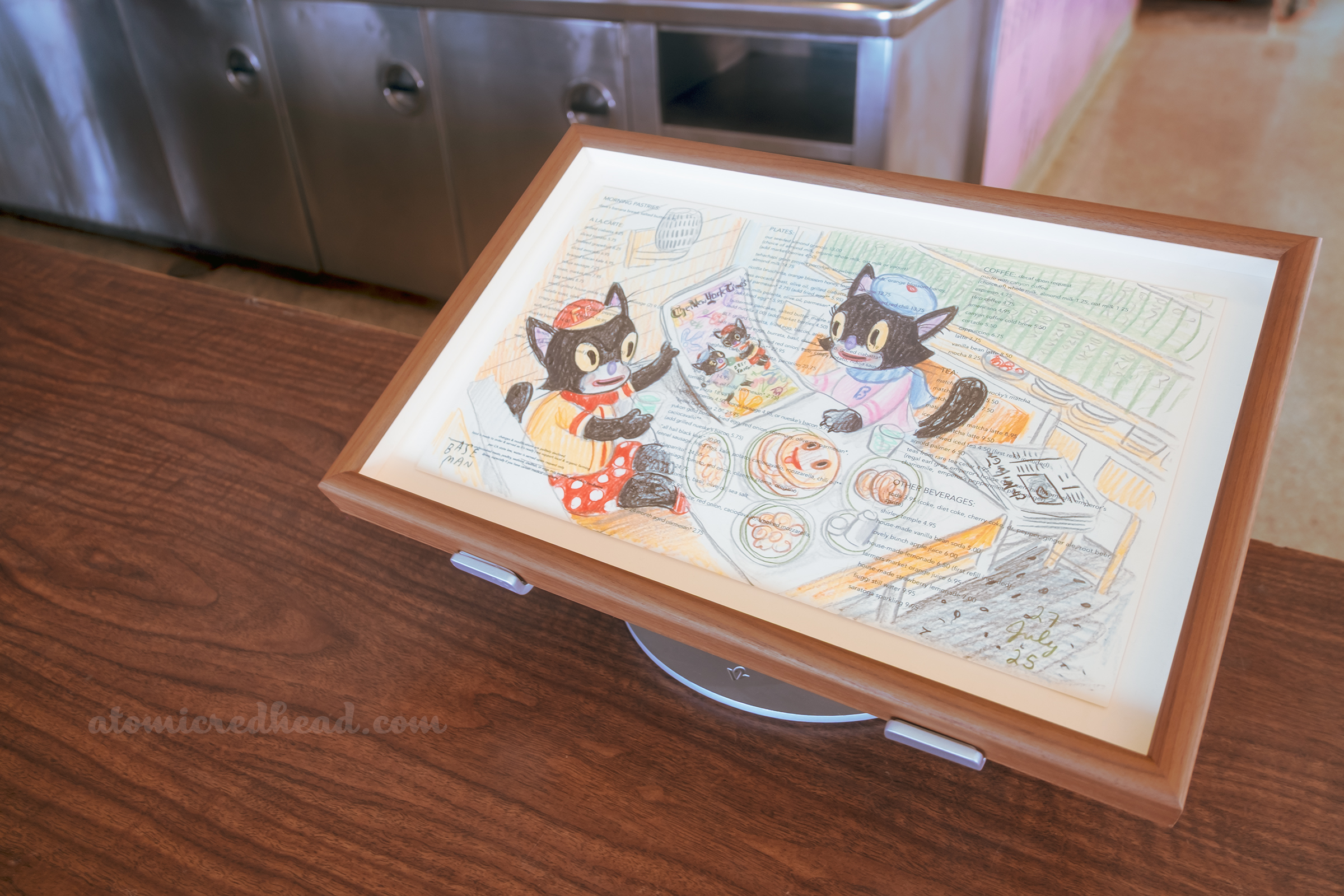 One of Baseman's works, this one features features two black cats looking at a newspaper.