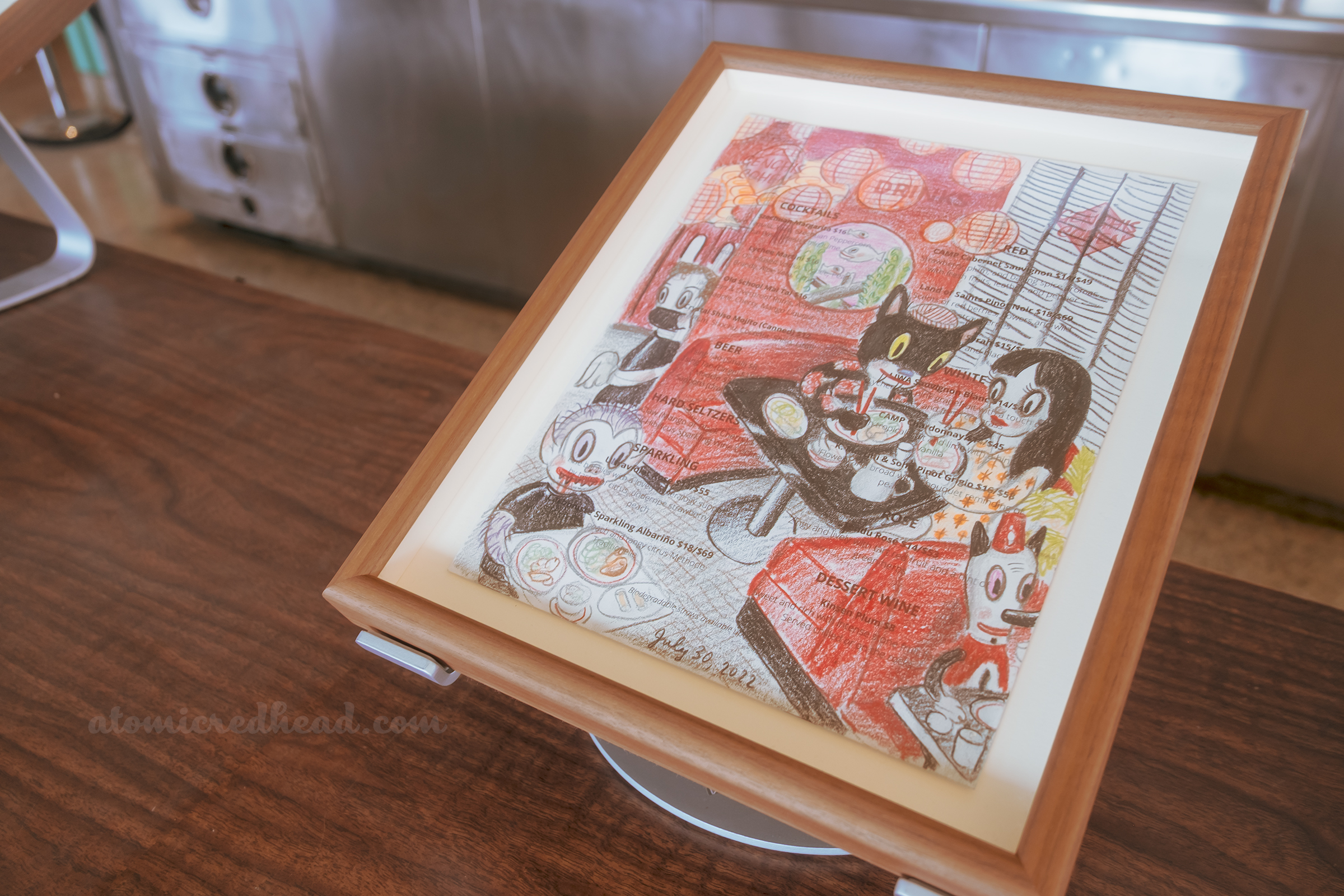 One of Baseman's works, this one features a dark haired woman seated in a round booth with a black cat.