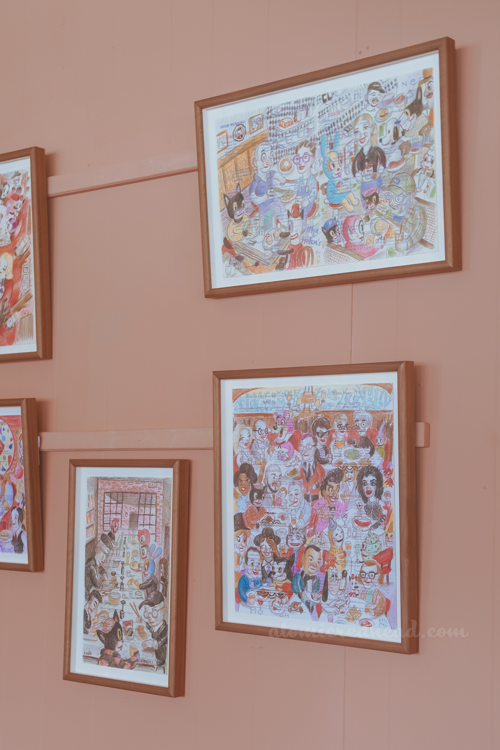 A collection of Baseman works hanging on a pink wall.