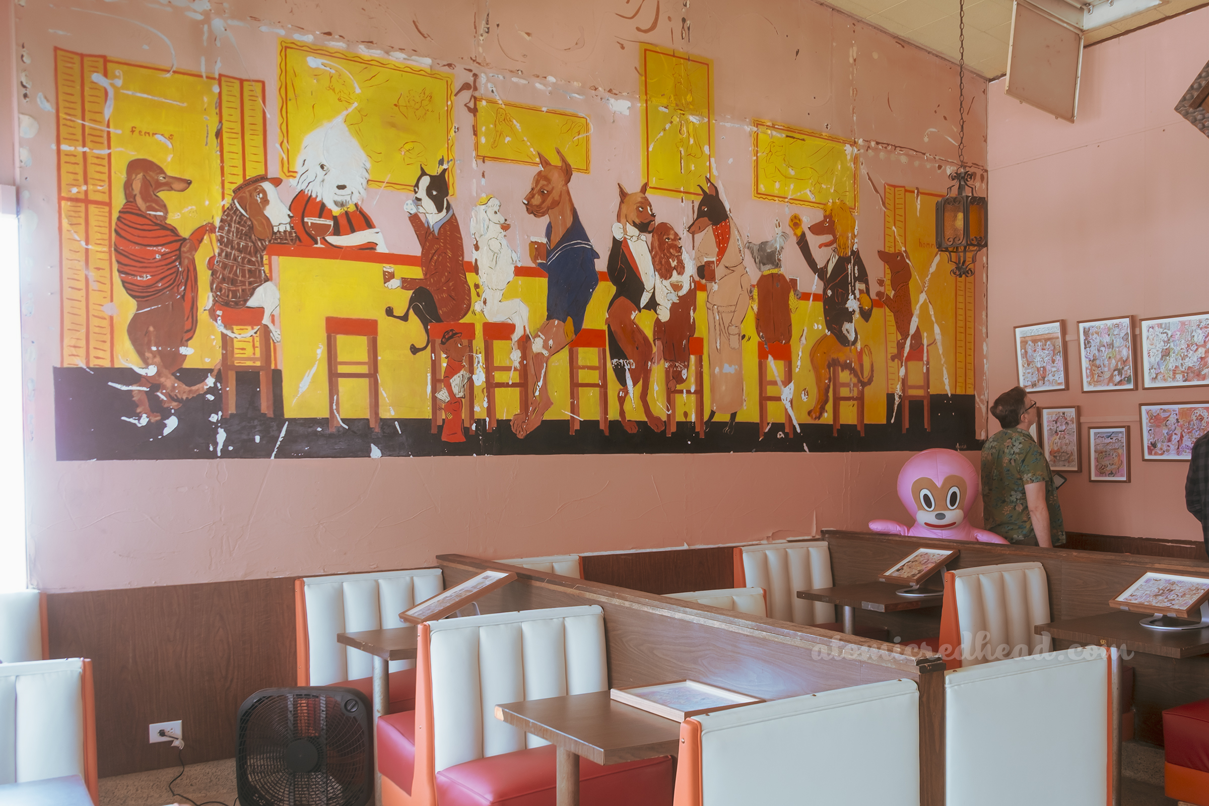 Wide view of the dog mural, which features various dog breeds dressed in fancy clothes at a bar.