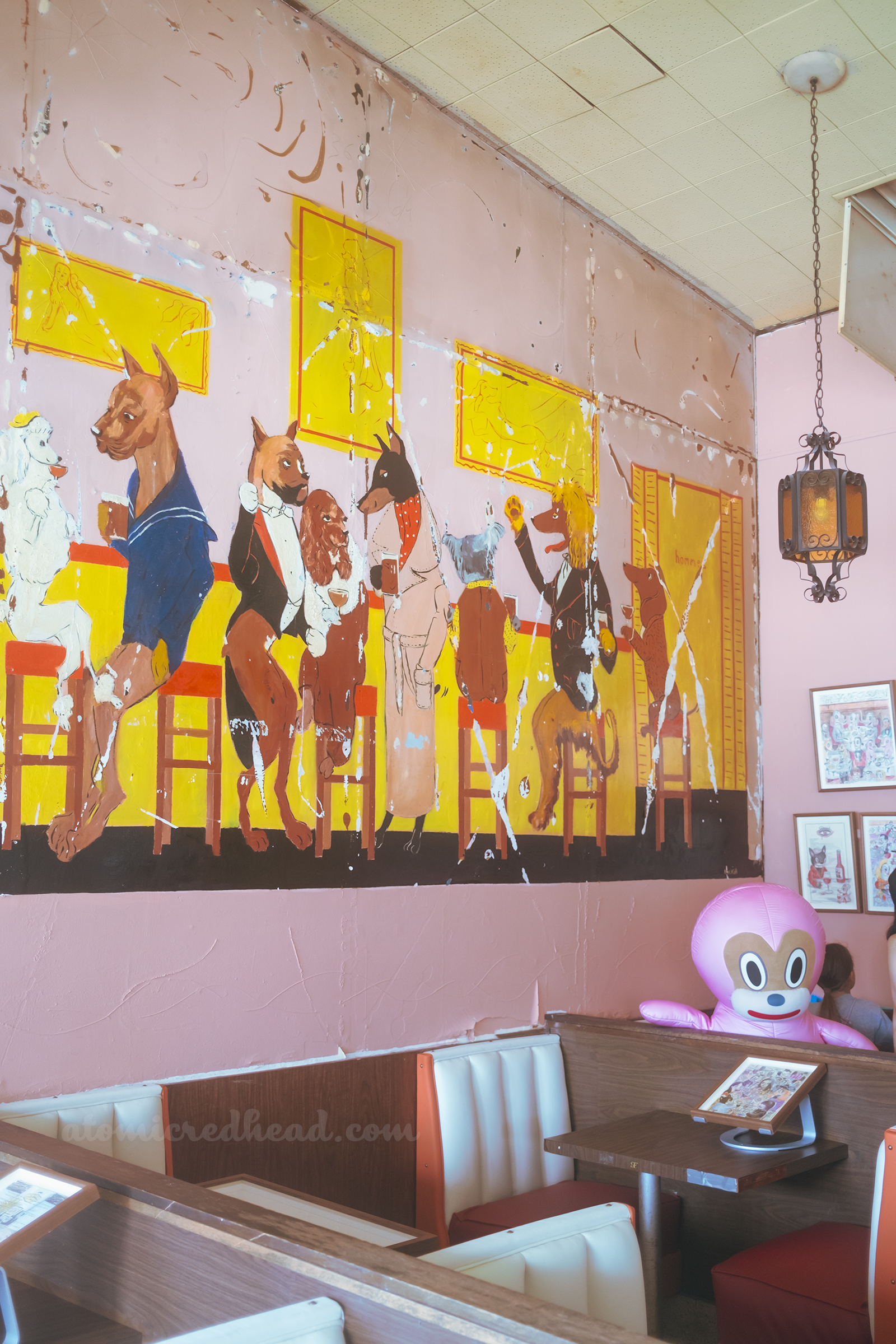 Wide view of the dog mural, which features various dog breeds dressed in fancy clothes at a bar.
