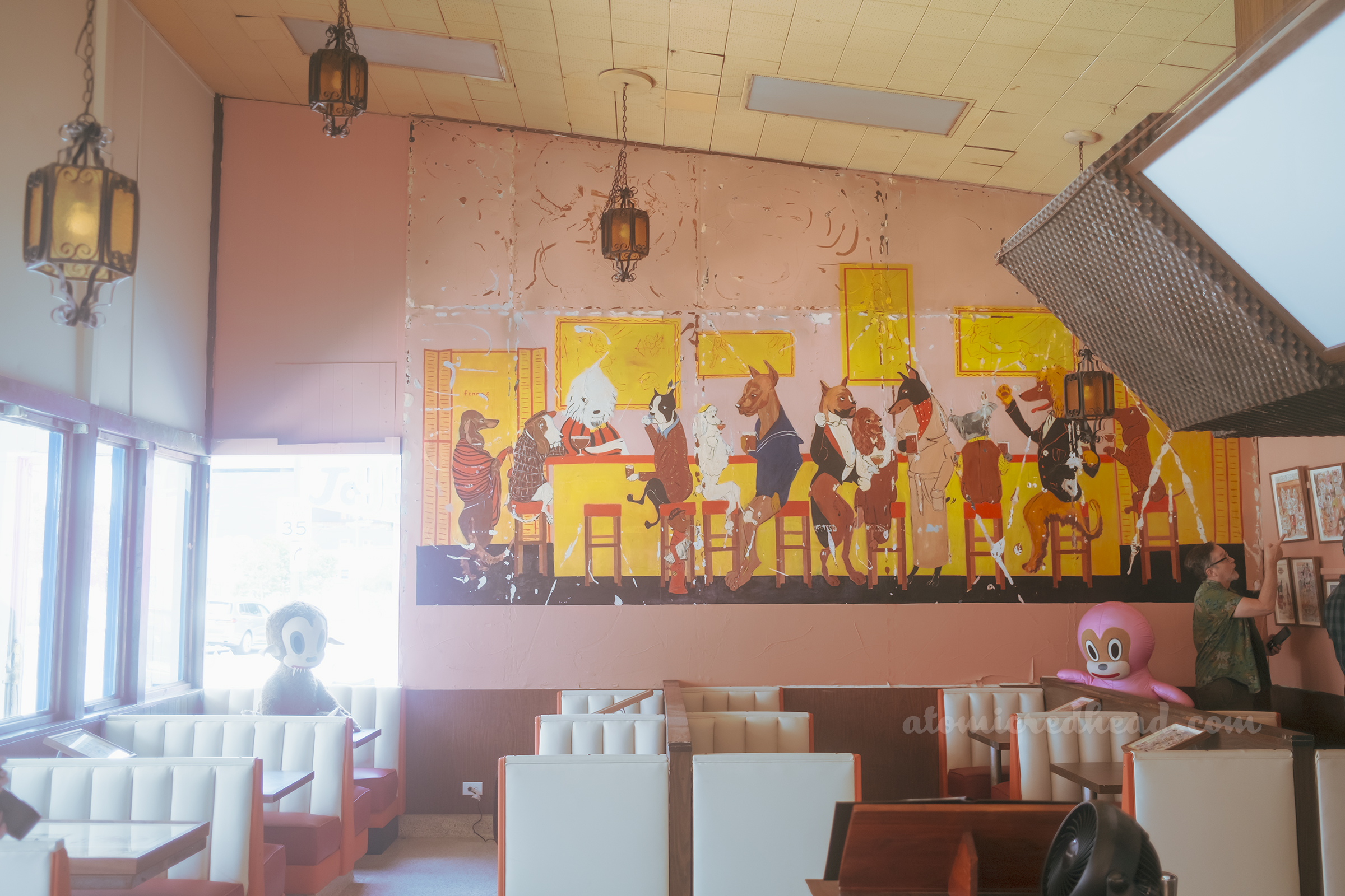 Wide view of the dog mural, which features various dog breeds dressed in fancy clothes at a bar.