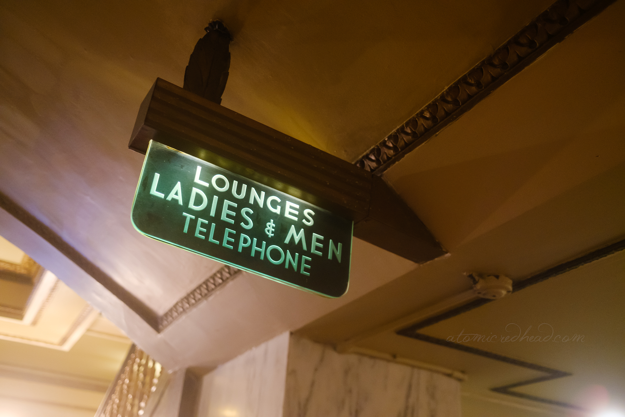 A green lighted sign reading "Lounges Ladies & Men Telephone"