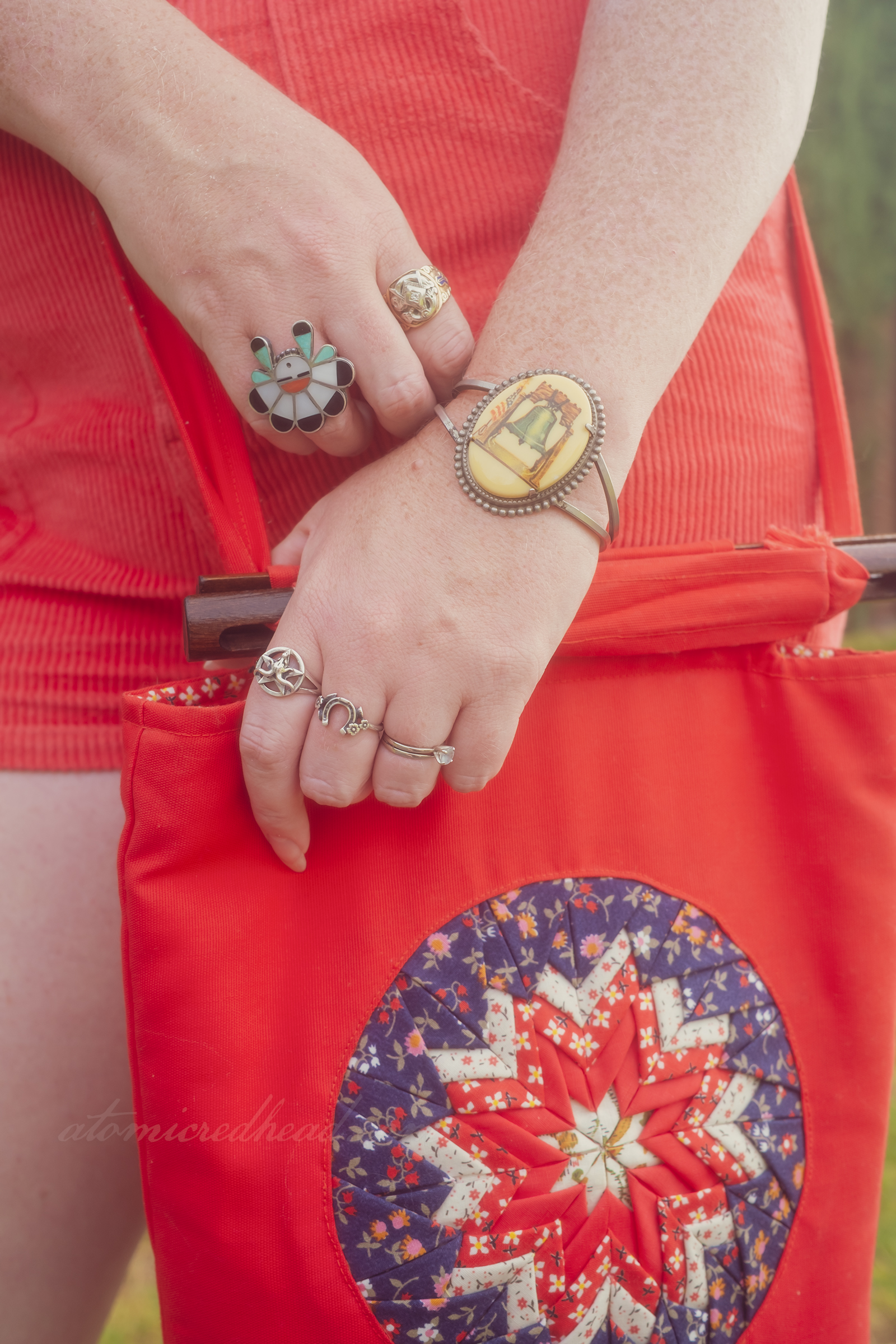 Close-up of my jewelry, including a bracelet featuring the Liberty Bell, and my quilted red, white, and blue purse.