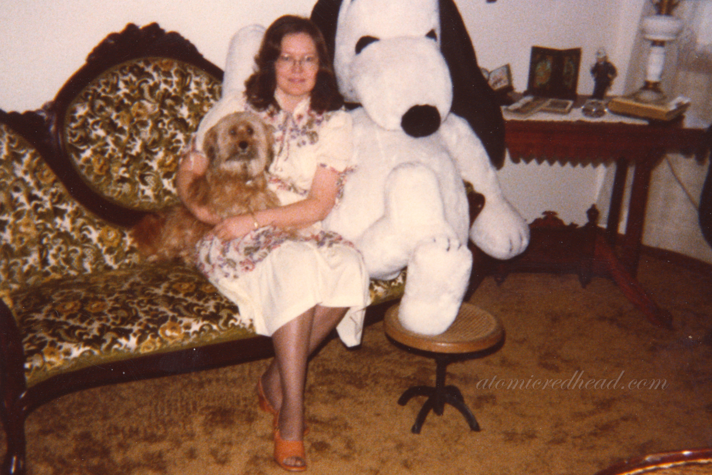 Photo of my mom on a Victorian couch with the family dog, Tuffy, and a large plush of Snoopy.