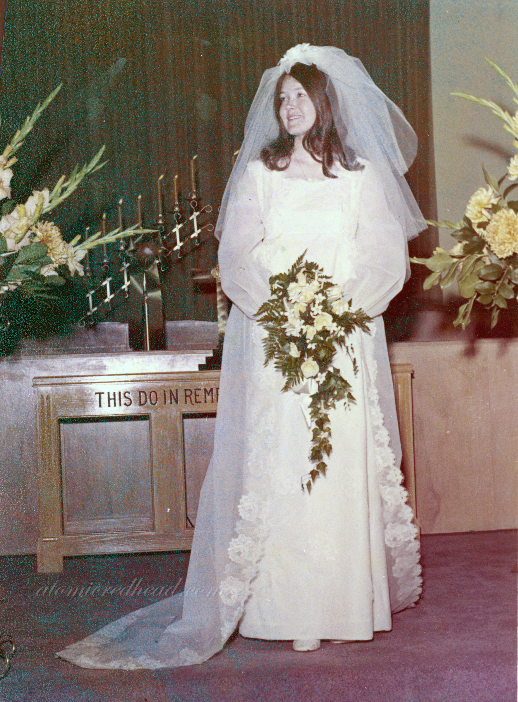 My mom on her wedding day in her dress with a bouquet of yellow flowers.