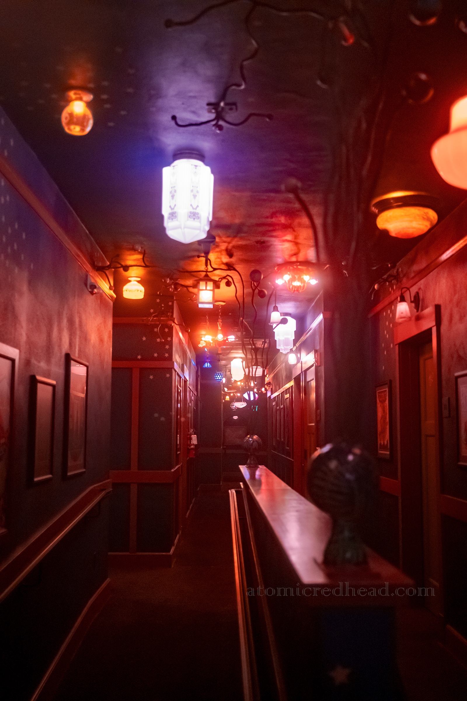 Hallway on the third floor, painted dark blue with a variety of colorful lights hanging.