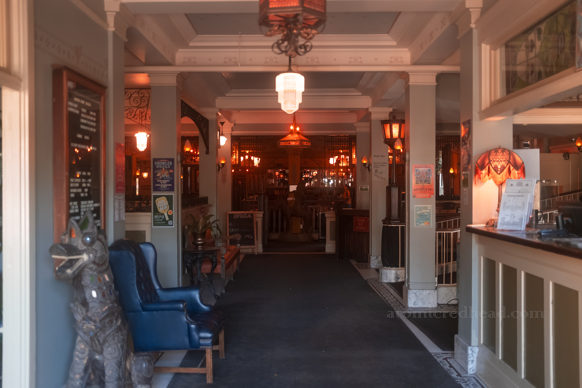 Lobby of the hotel, with the check in desk on the right, walls and columns painted a pale green and unique light fixtures abound.