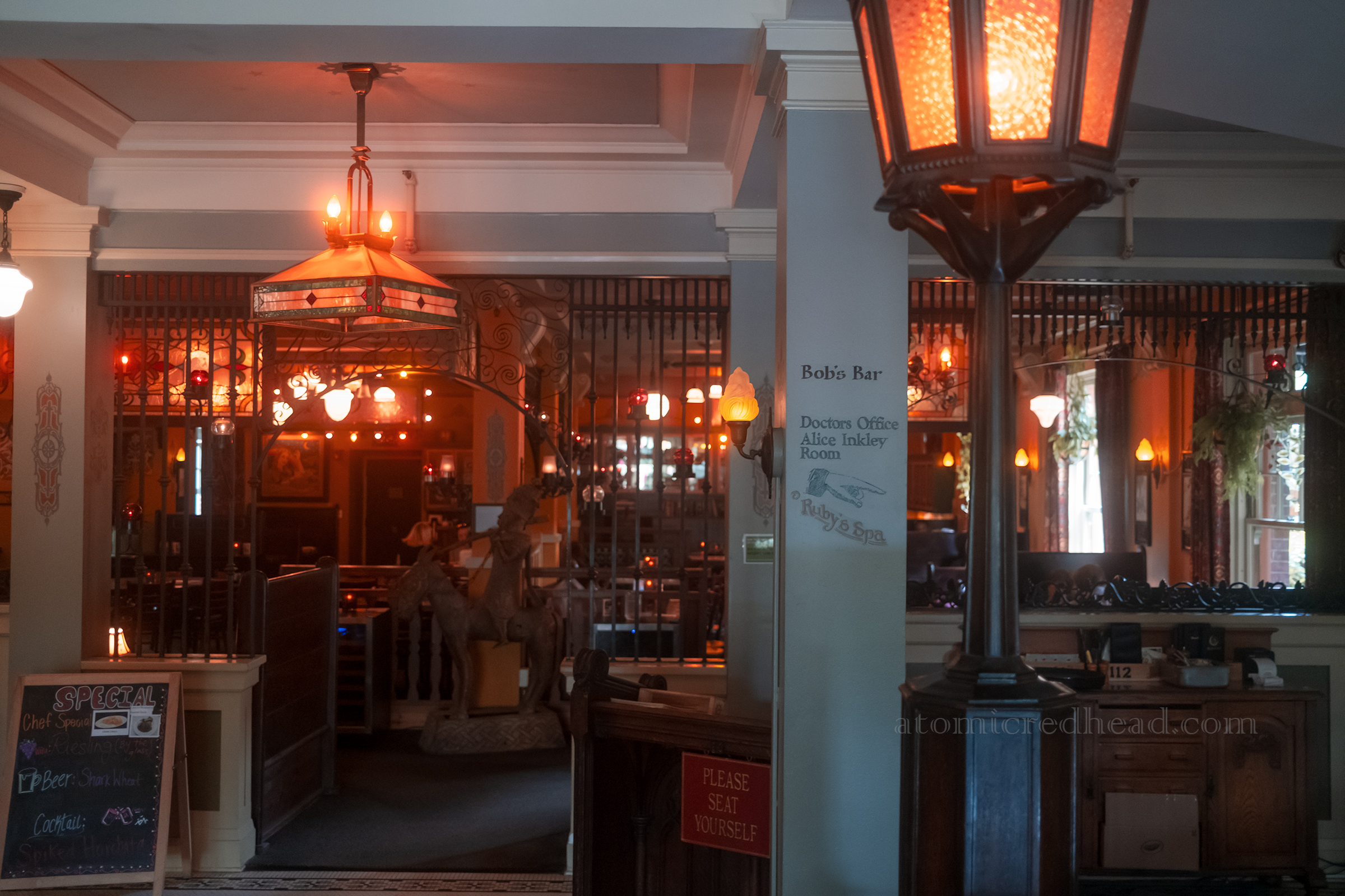 View of the restaurant just past the check in desk, with works of art done in metal and various unique light fixtures.