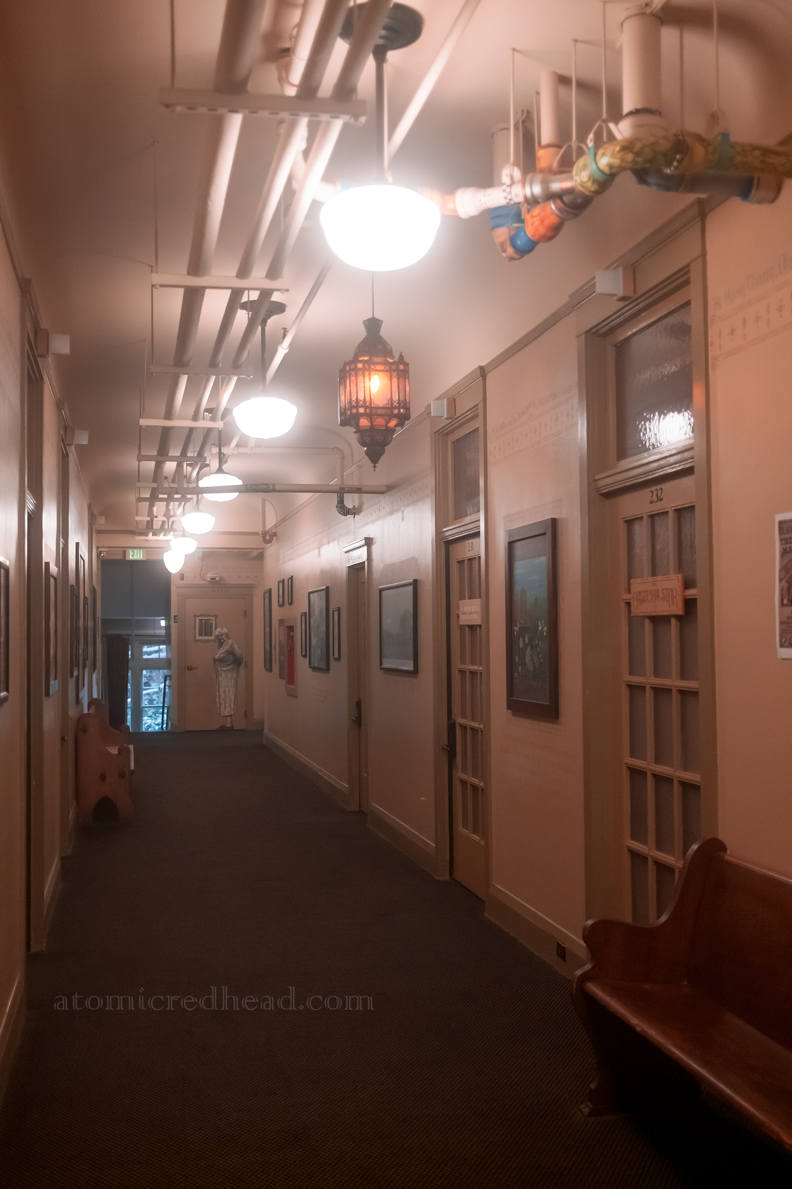 One of the hallways, painted in a pale tan, with unique light fixtures and various paintings.