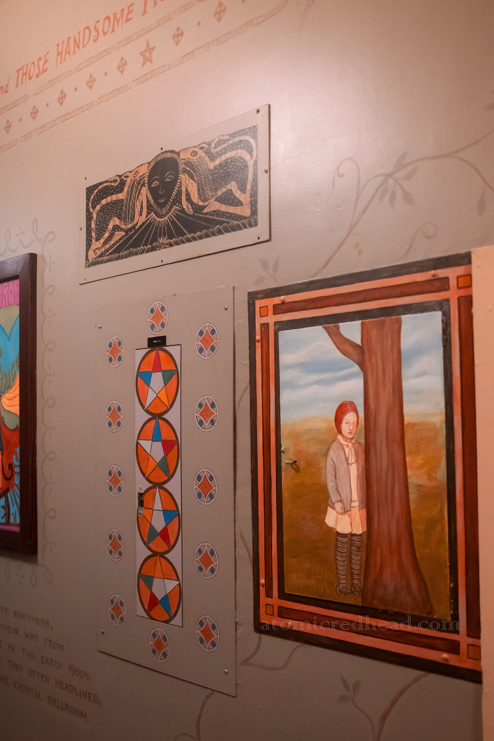 A mural of a child by a tree, and an electrical panel door is painted in the Eastern Star motif.