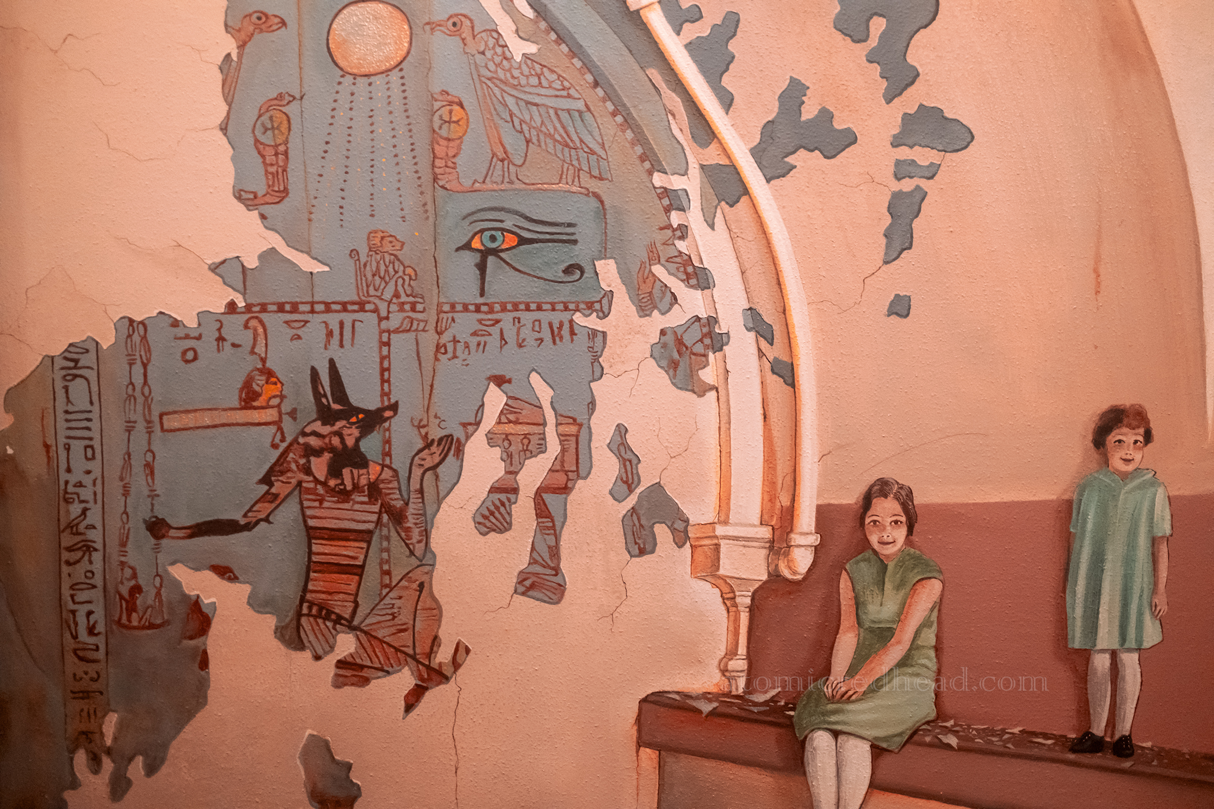 A mural featuring Egyptian motifs, and children on a bench.