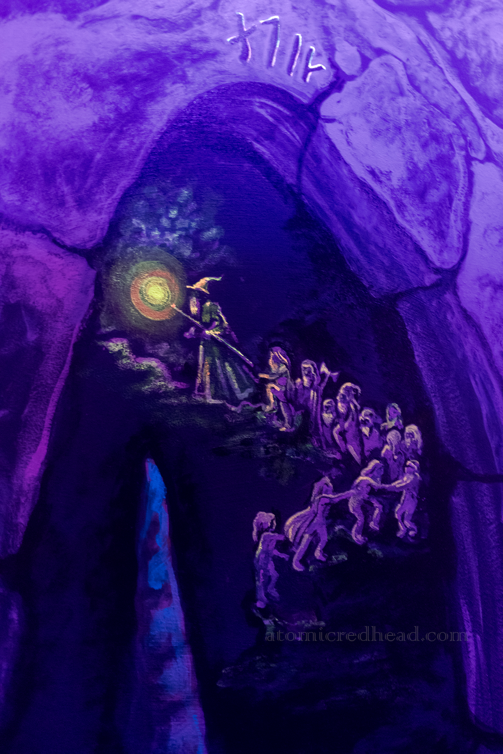 A blacklight mural of a cave featuring images from The Hobbit. Here Gandalf leads the hobbits up a staircase.