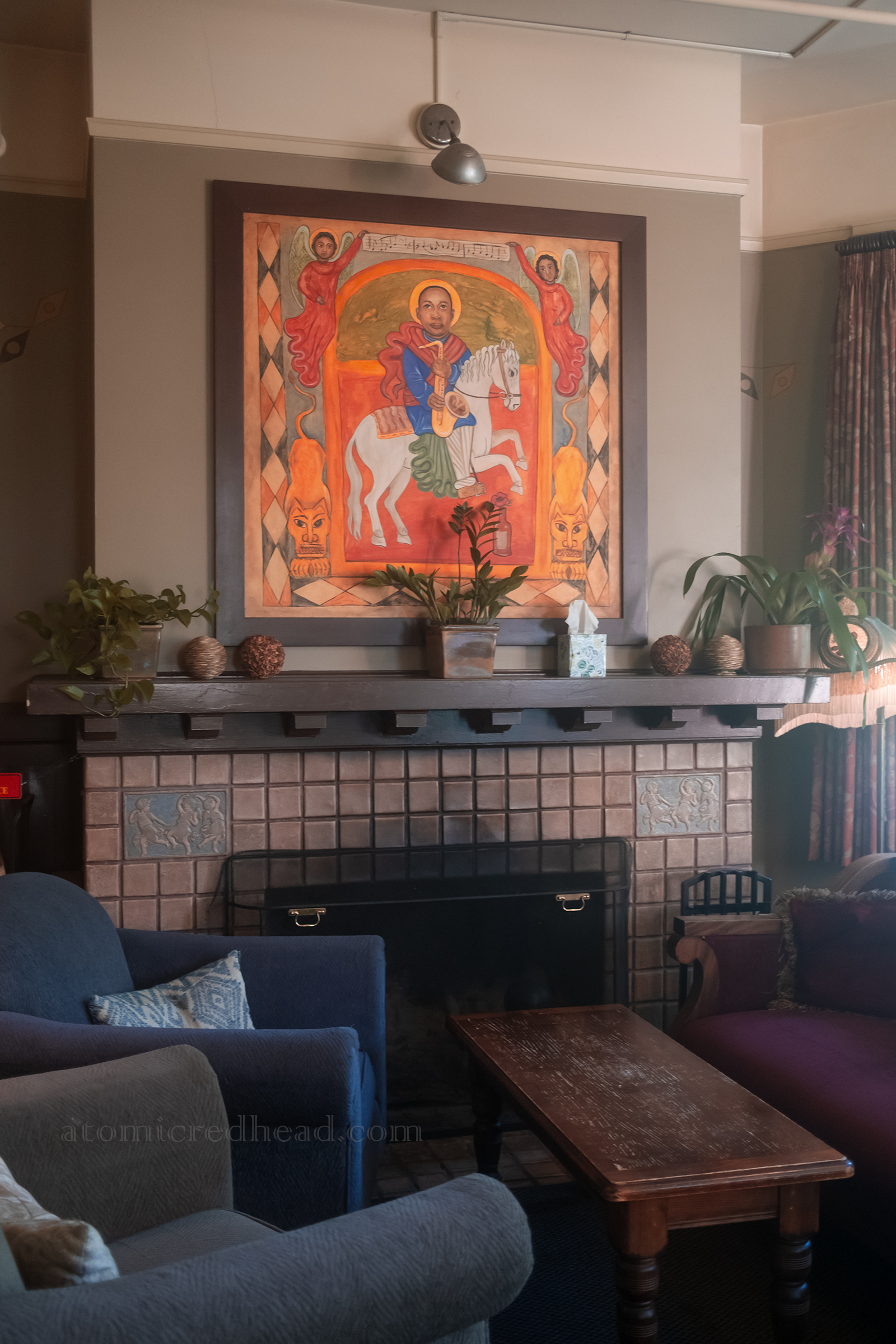 A painting of a man on a horse above a fireplace.