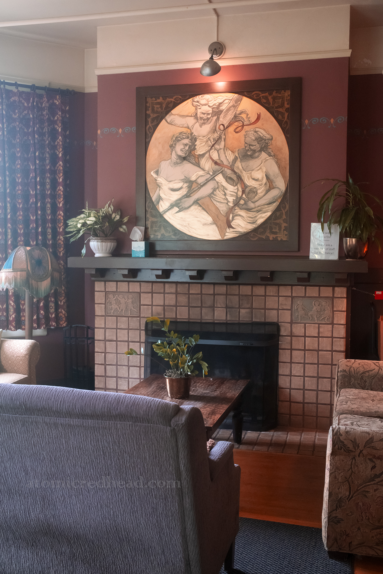 A painting of three women above a fireplace.