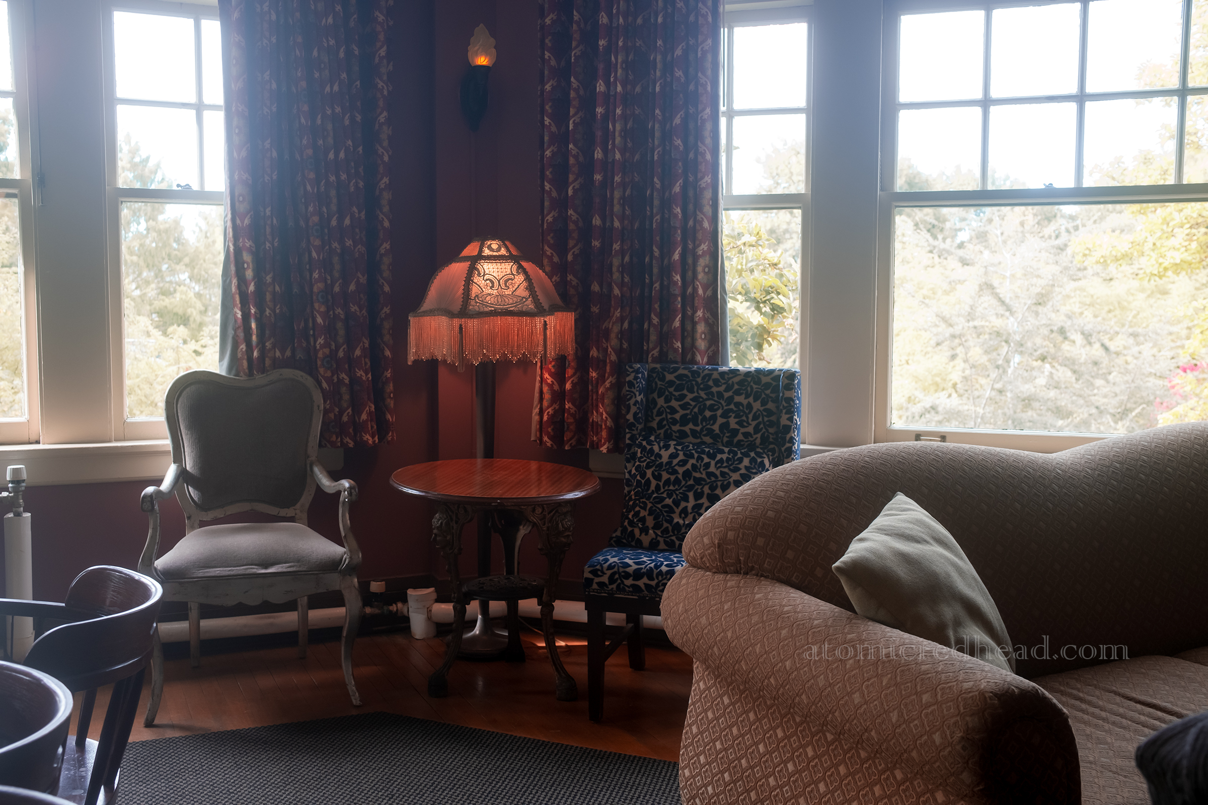 A lush parlor with chairs and couch and fringed lamps.