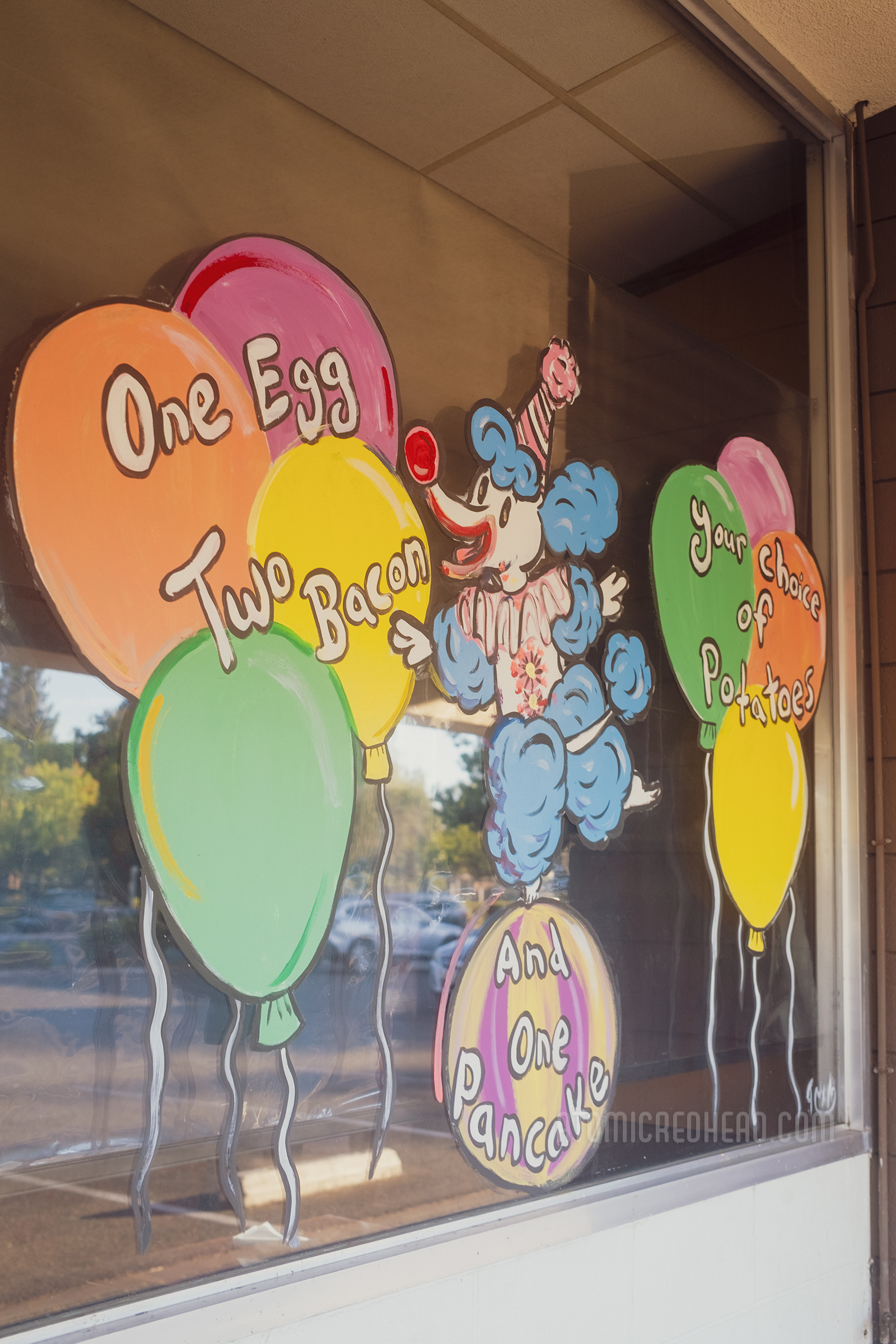 Painted on one window is a clown poodle balances on a ball surrounded by balloons.