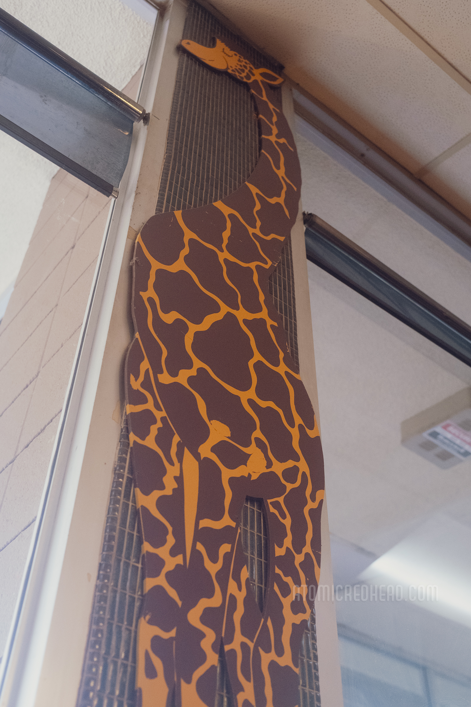 A large cut out giraffe hangs in between the windows inside.