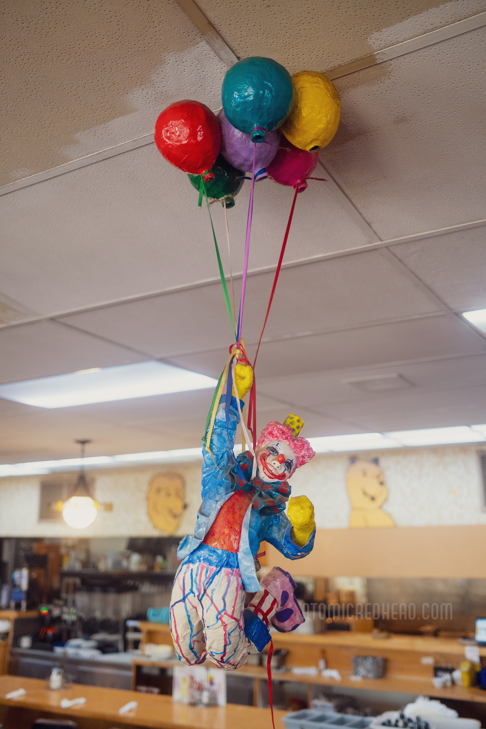 A clown holding onto balloons hangs from the ceiling.