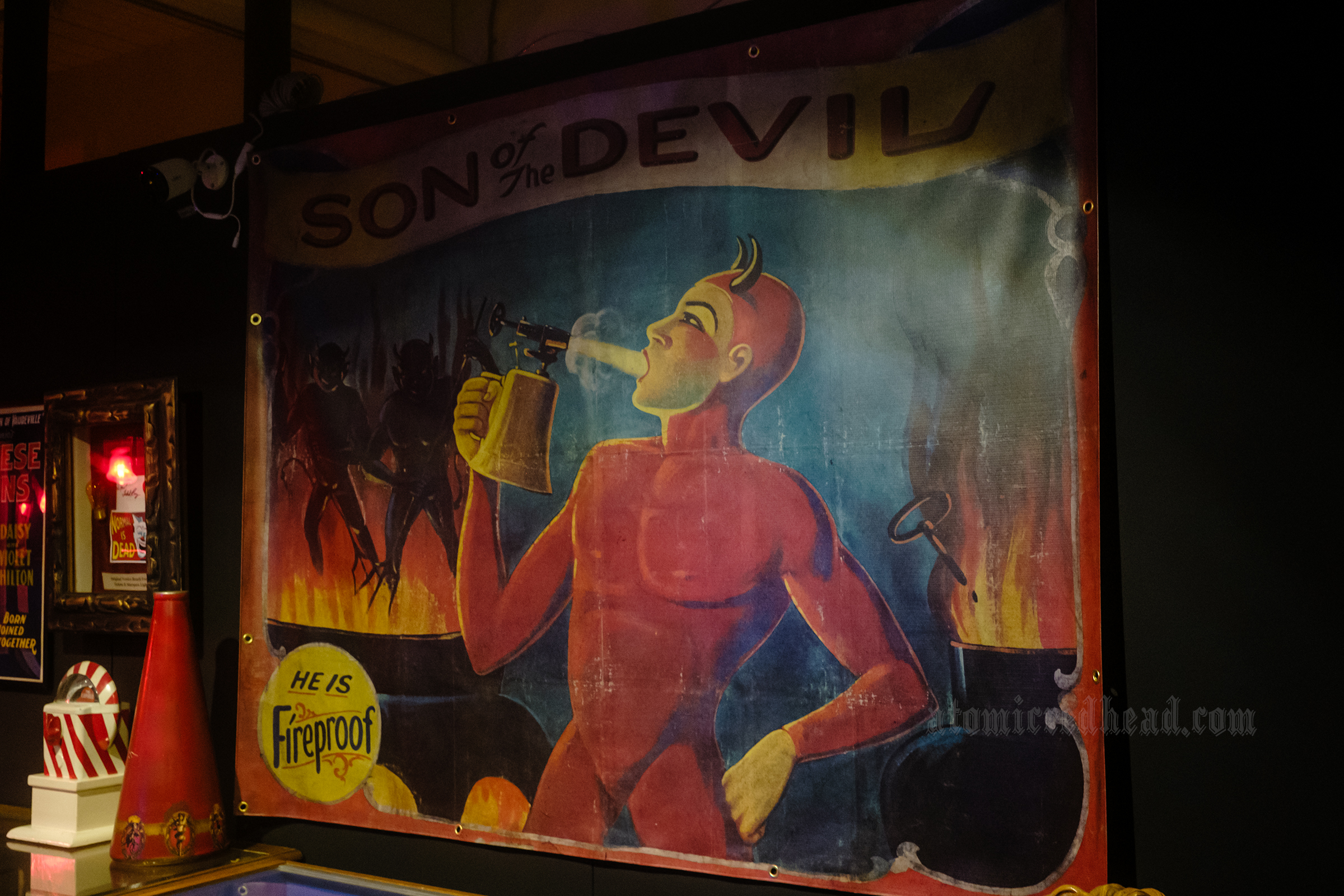 A sideshow poster of a boy in a devil costume blowing a fire extinguisher into his mouth. Across the top it reads "Son of the Devil"