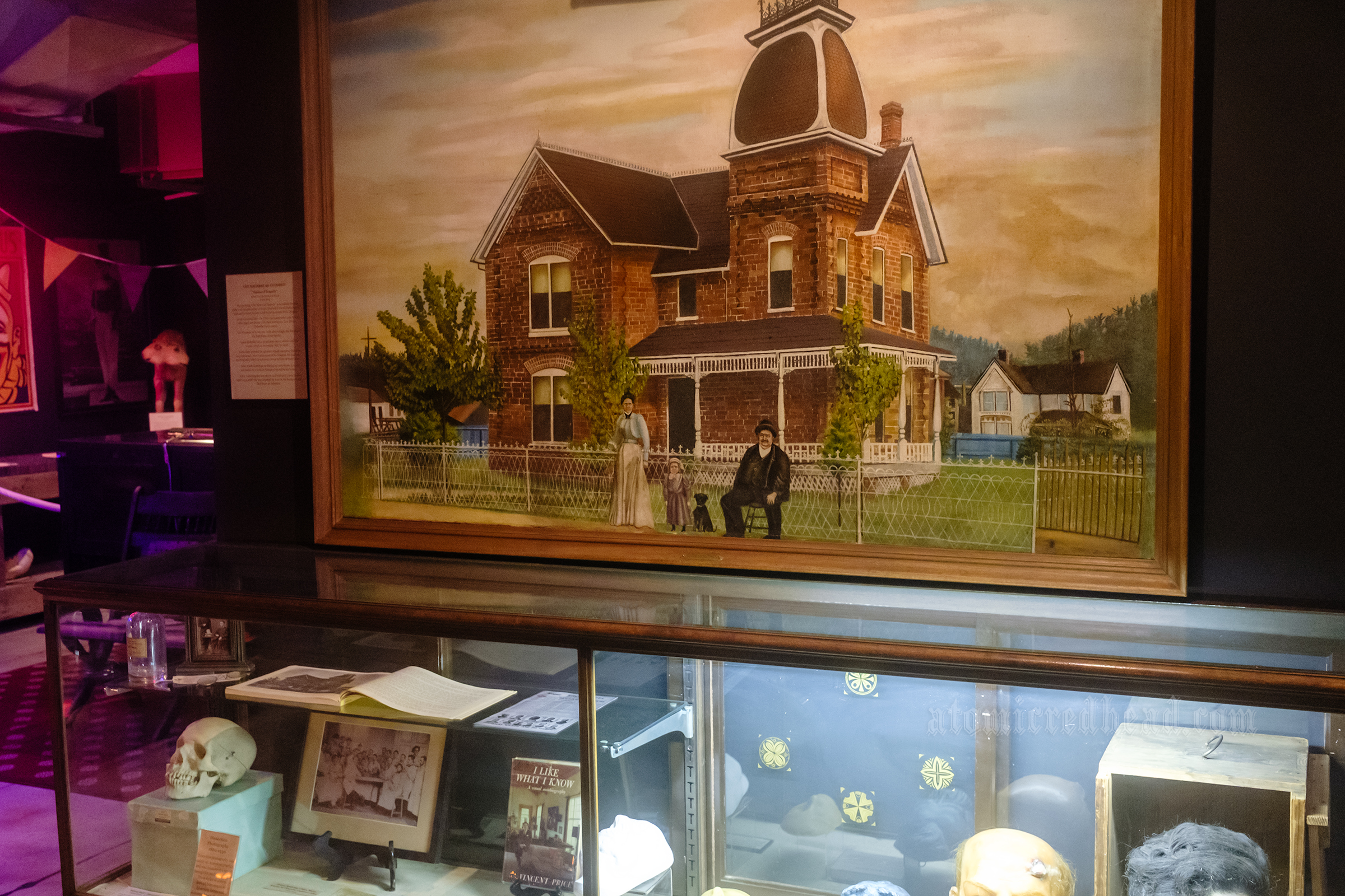 A large painting of a Victorian brick mansion.