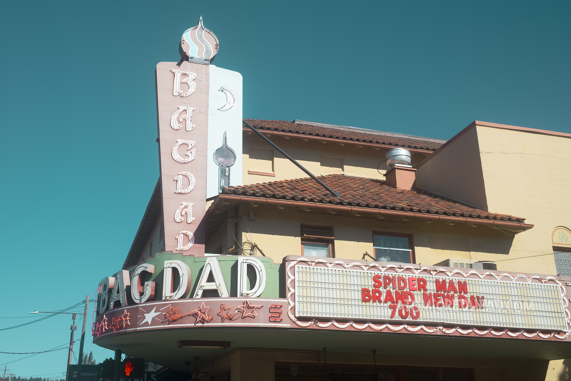 A large red tile roof building features a neon marquee and blade style sign each reading "Bagdad" 