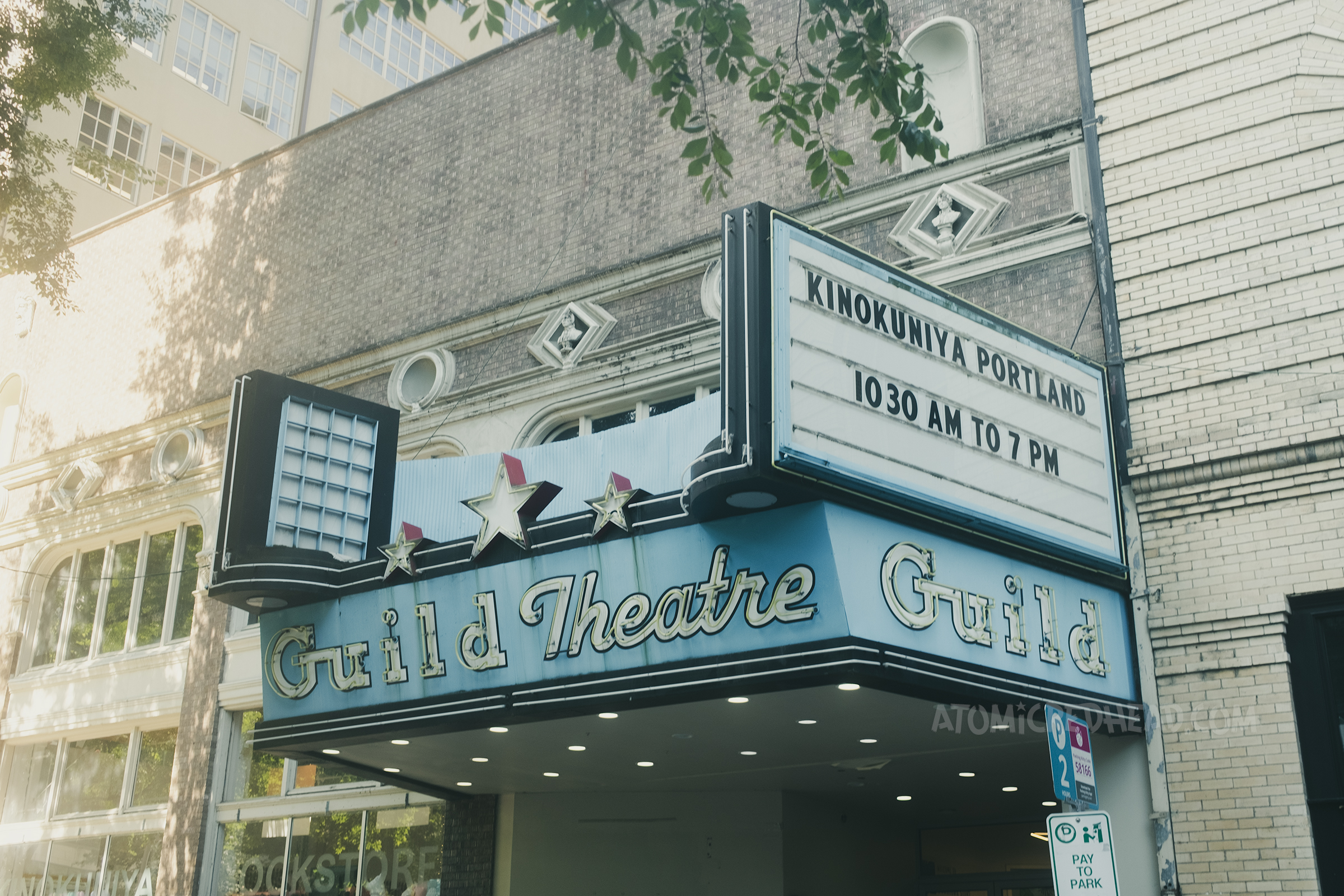 A blue sign juts out from a brick building and in neon it reads "Guild Theatre"