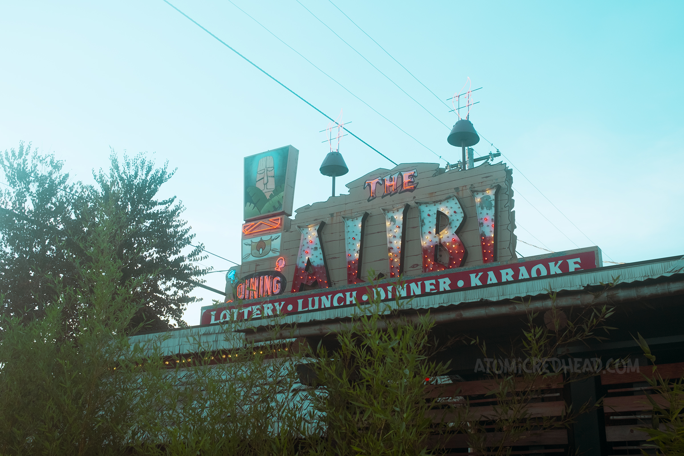 A large neon and bulb sign reads "The Alibi" and features a tiki on it.