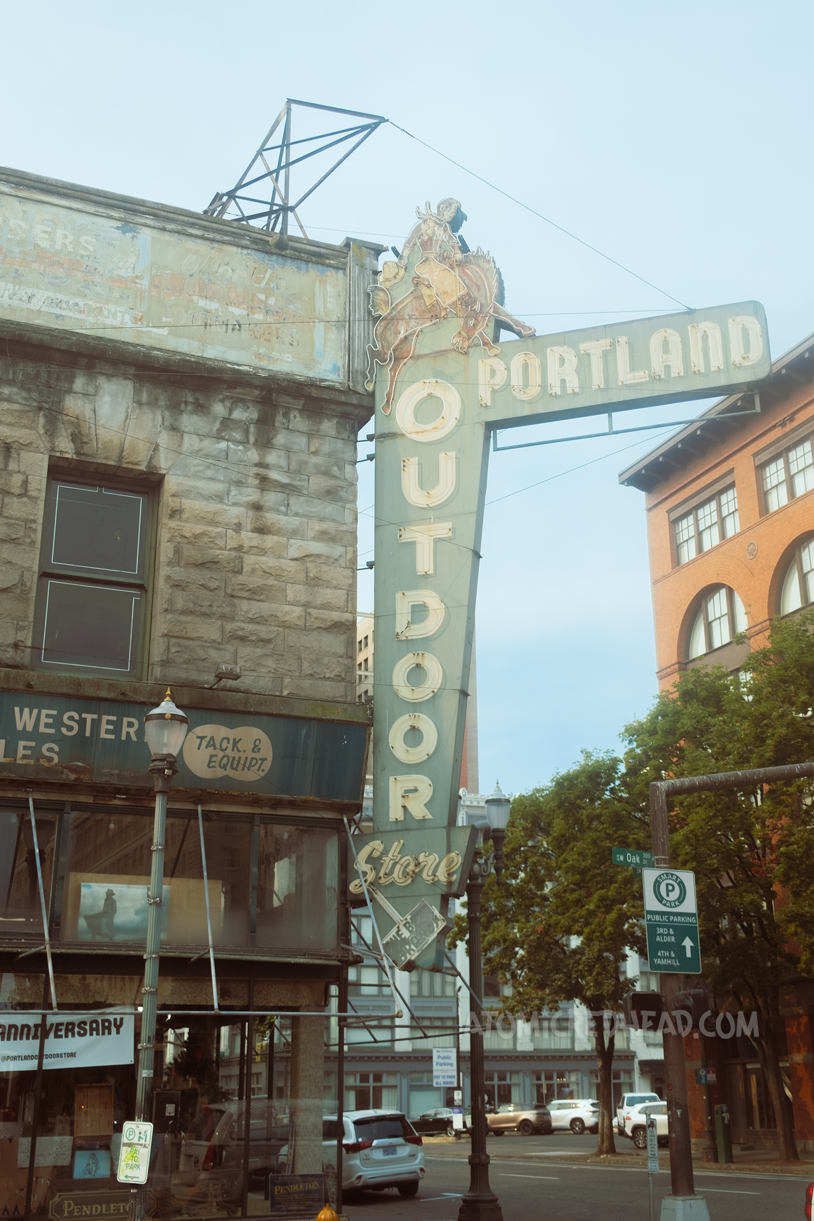 A large blade style neon sign reads "Portland Outdoor Store" and features a cowboy on a bucking horse.