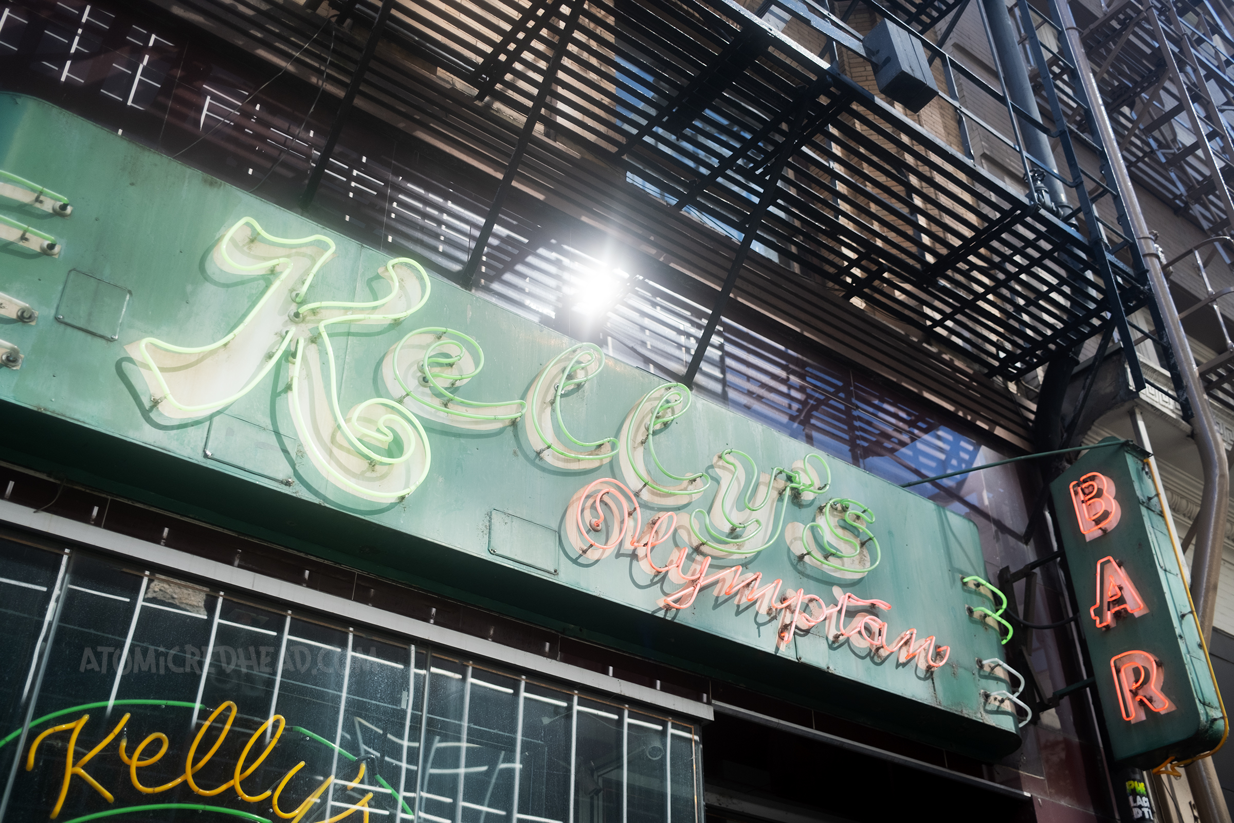 Green neon sign reads "Kelly's Olympian" 
