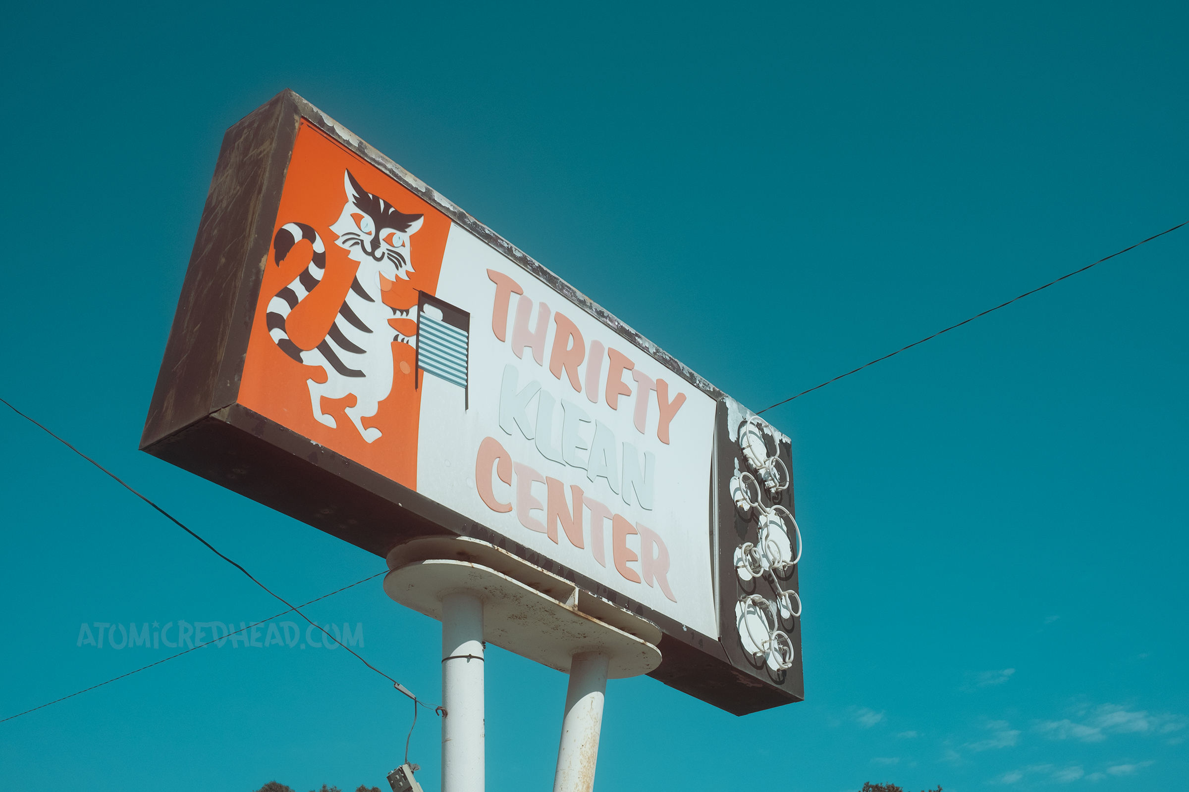 A colorful backlit plastic sign features a cat with a washboard and it reads "Thrifty Klean Center" with neon bubbles down the side.