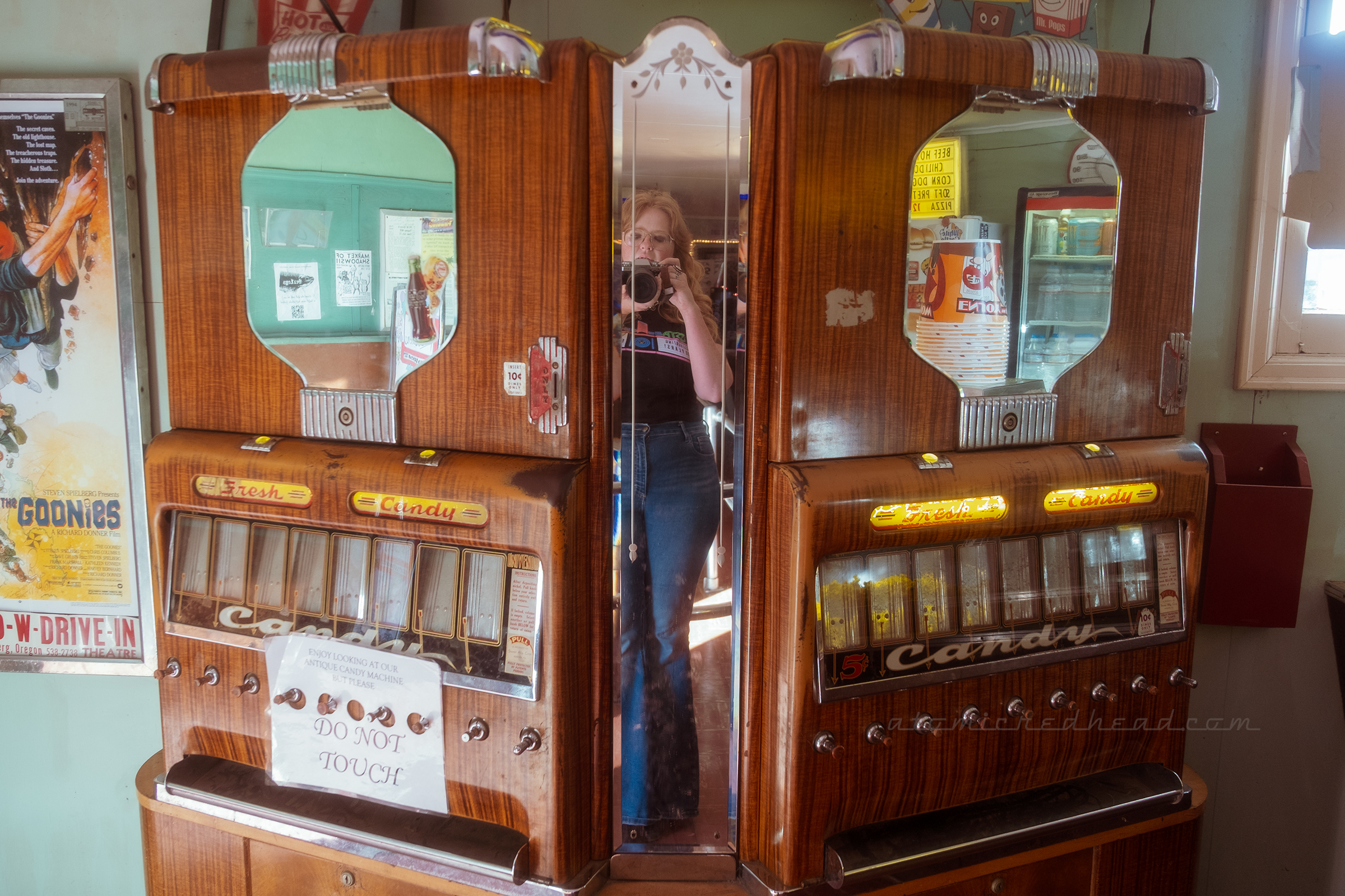 A reflection of myself in the mirror of a vintage candy vending machine.