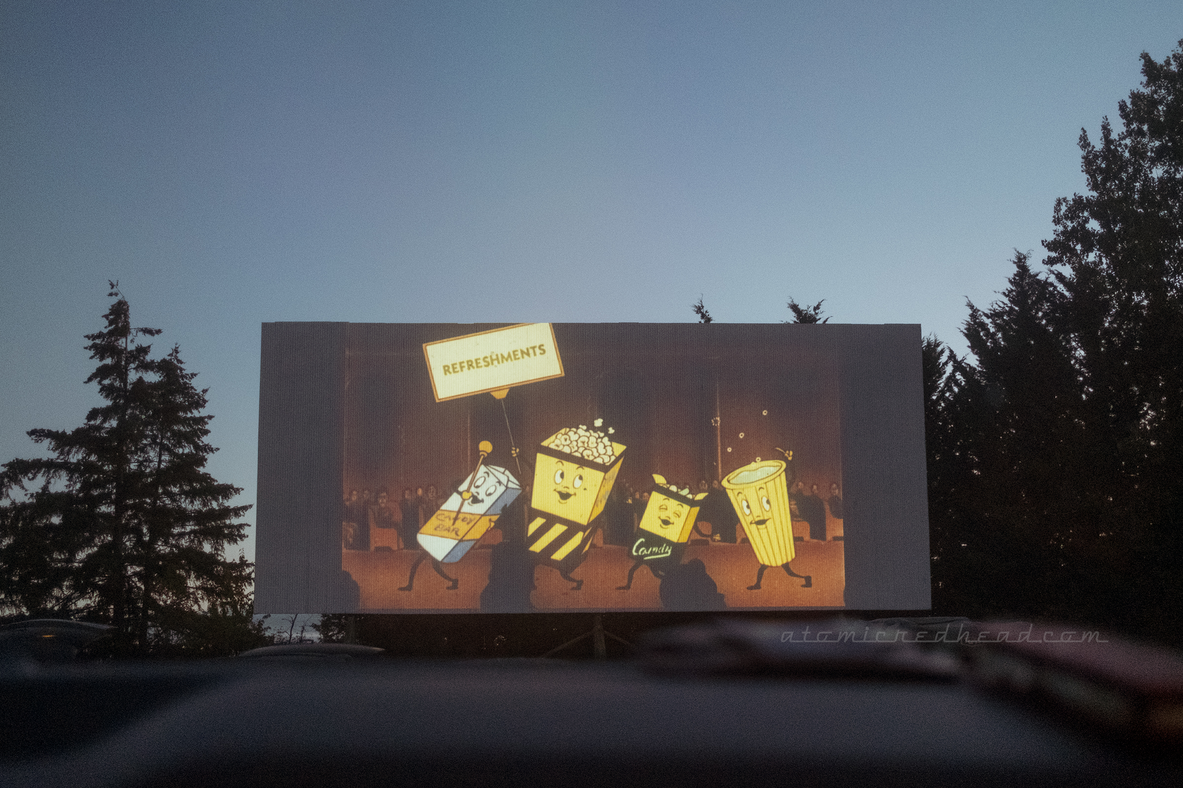 A vintage reel shows anthropomorphic candy, popcorn, and soda advertising what is available at the concession stand.