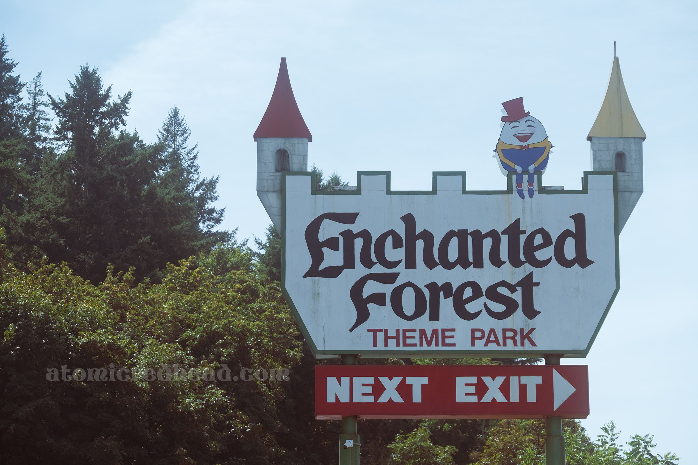 A large castle shaped sign with the egg character Humpty Dumpty sitting on top, reading "Enchanted Forest Theme Park Next Exit"
