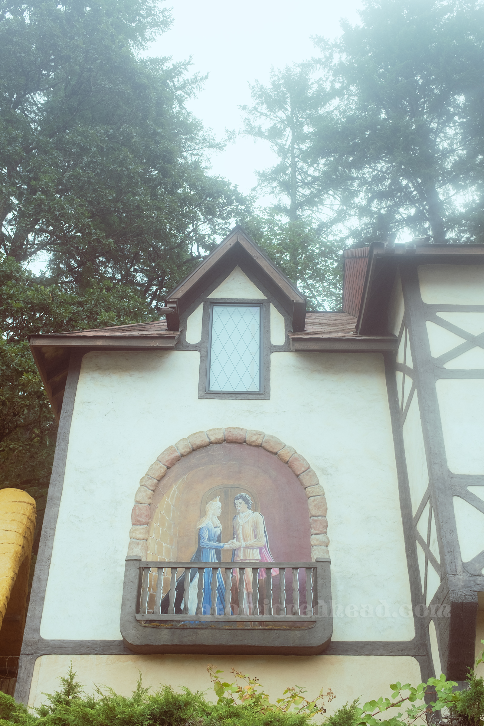 A medieval style building with a mural of a prince and princess on the side appearing as if they are on a balcony.