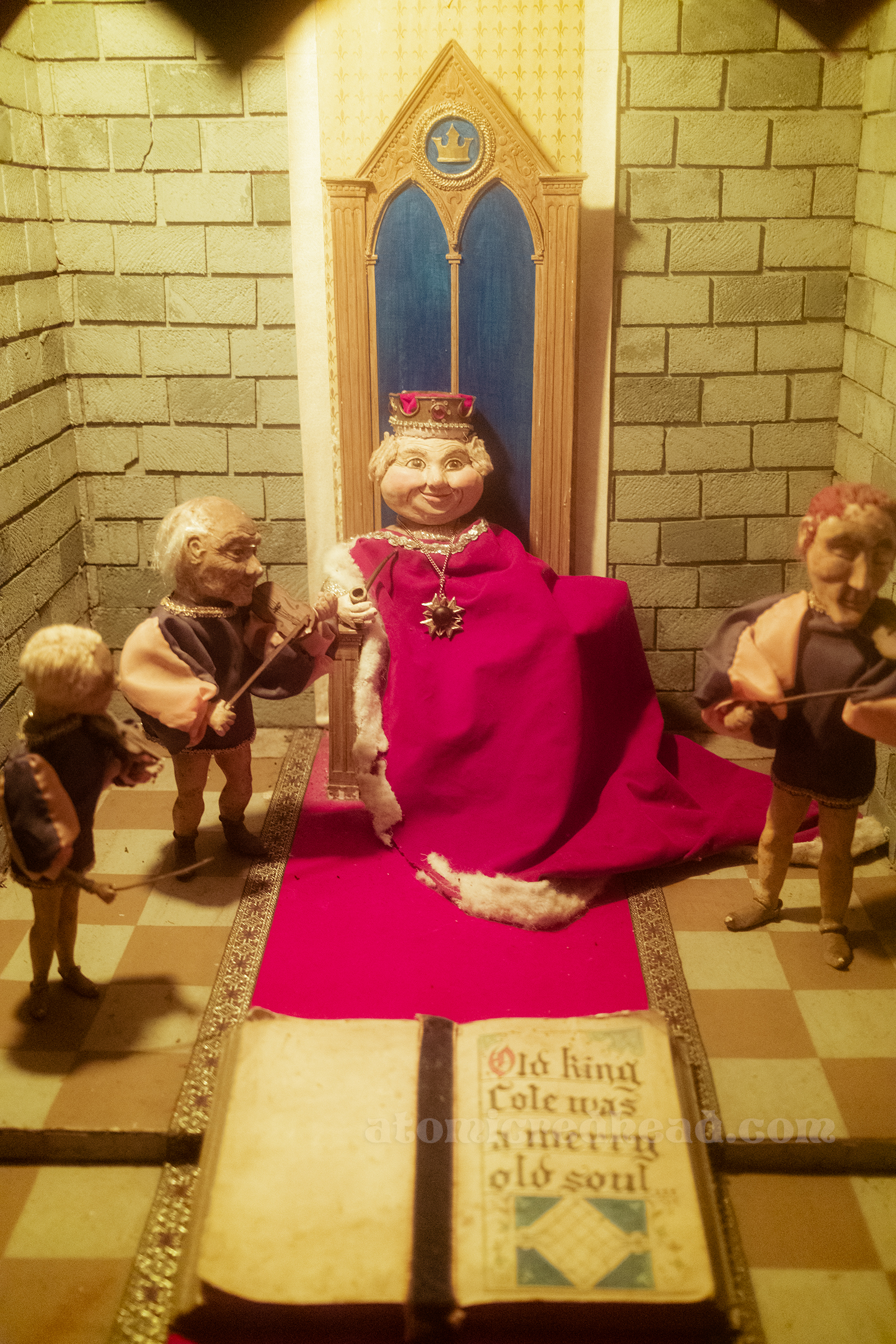 A small vignette of Old King Cole, a round king on a throne.