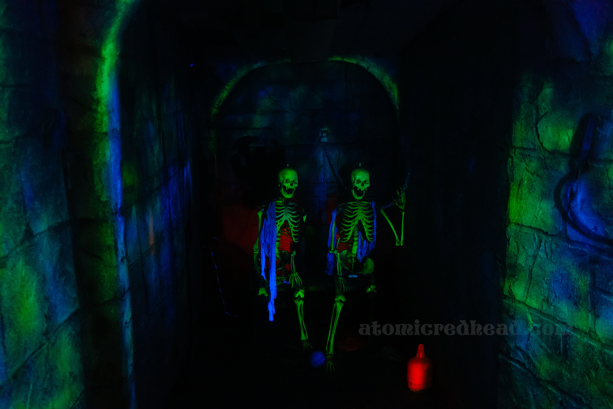 A pair of skeletons glow inside a dungeon. 