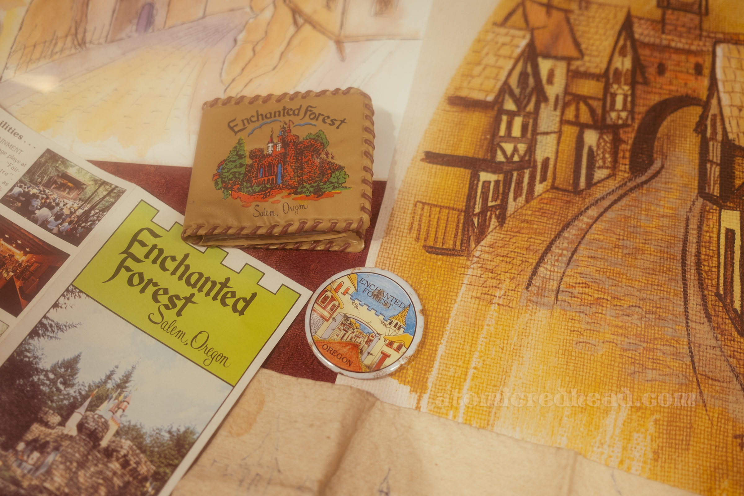 Close-up of early souvenirs, including a wallet with an image of the castle on it and a button with the English Village on it.