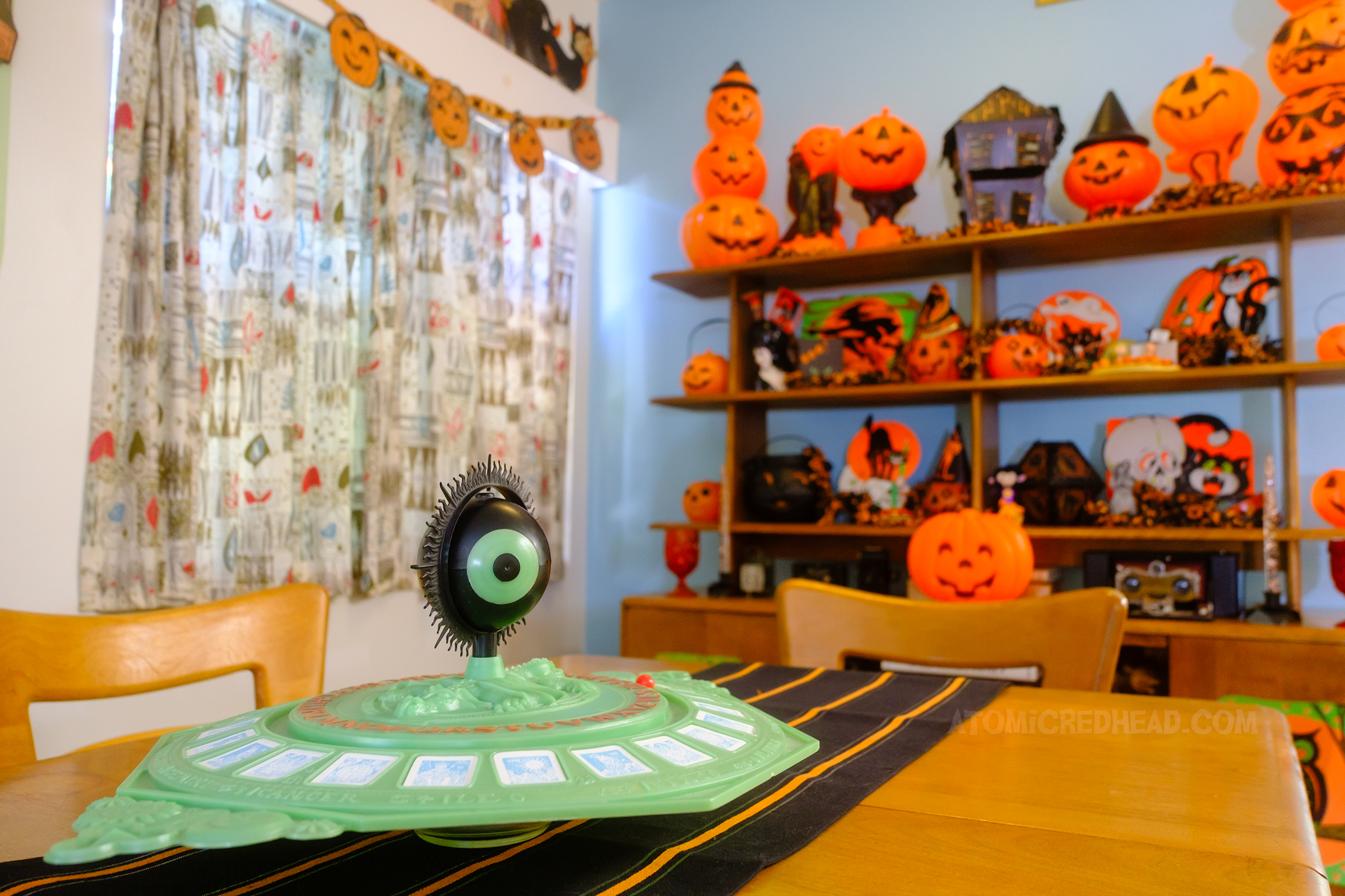 A unique spirit board, green, circular, with a large eyeball in the center.