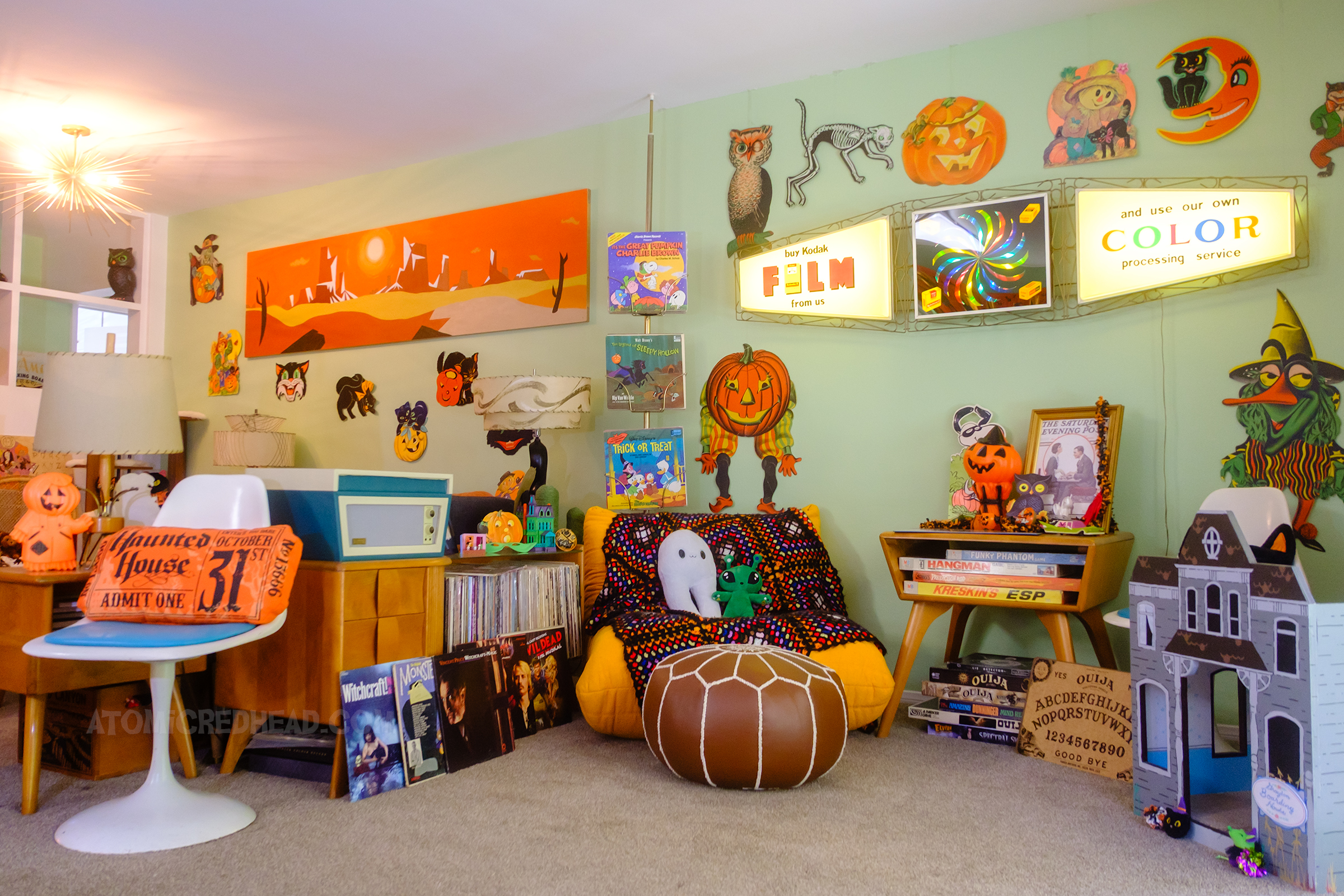 A record player sits on a console with various records nearby of the spooky variety.